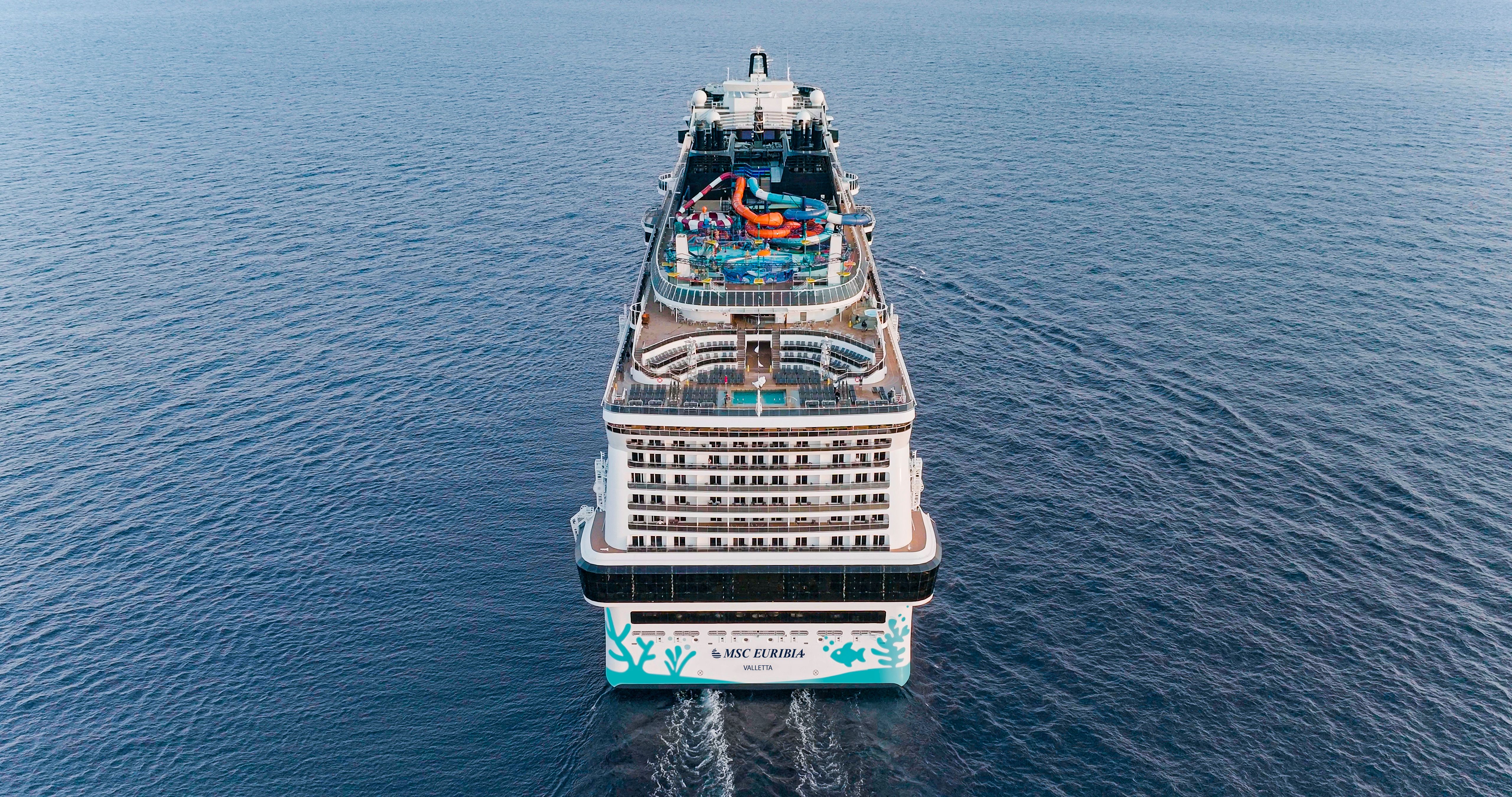 Aerial view of MSC Euribia cruise ship sailing at sea, showcasing top-deck water park, pools, and family-friendly amenities.