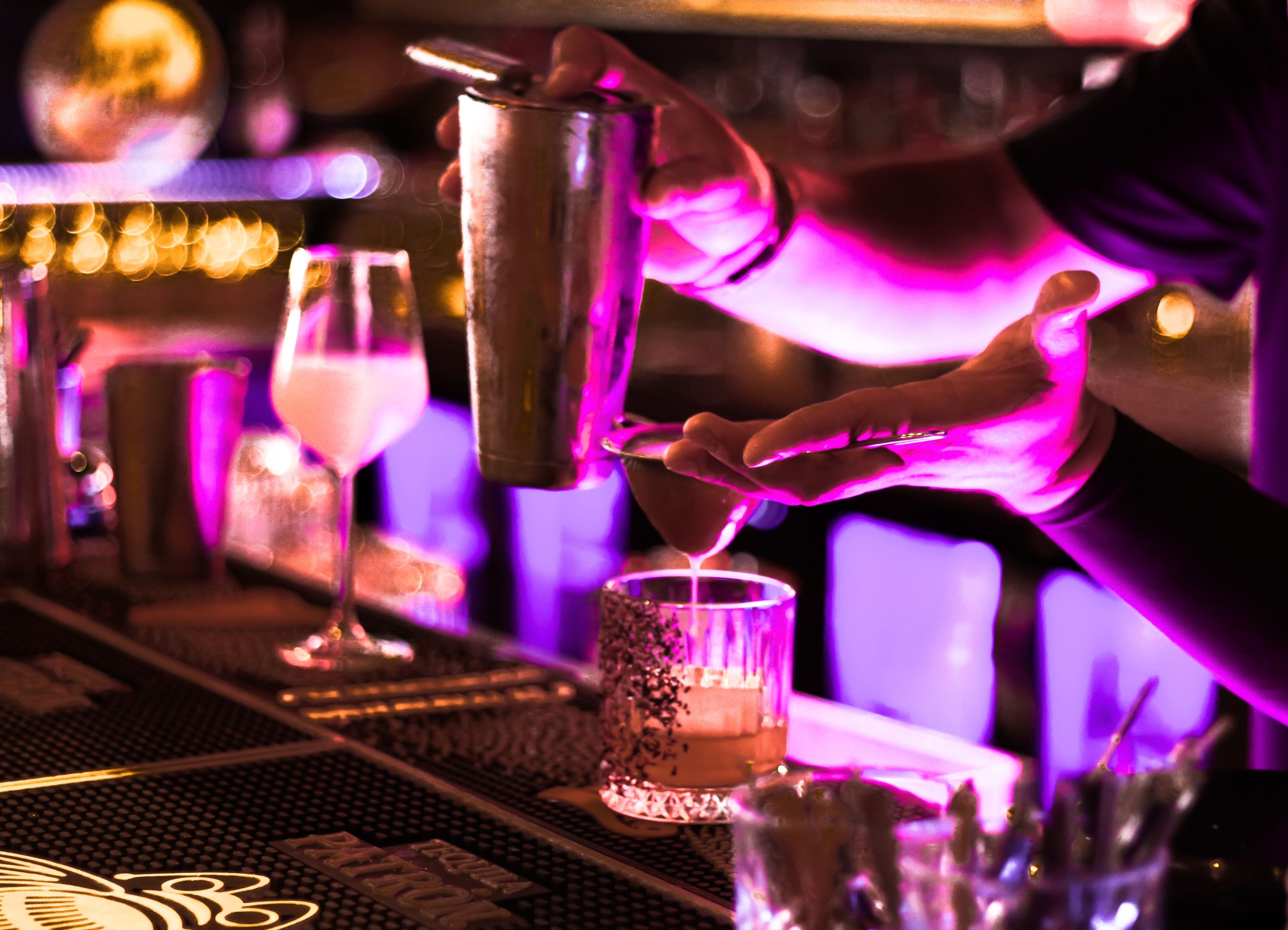 Bartender crafting a signature cocktail under vibrant pink lighting at a Princess Cruises bar, showcasing upscale nightlife and mixology at sea.