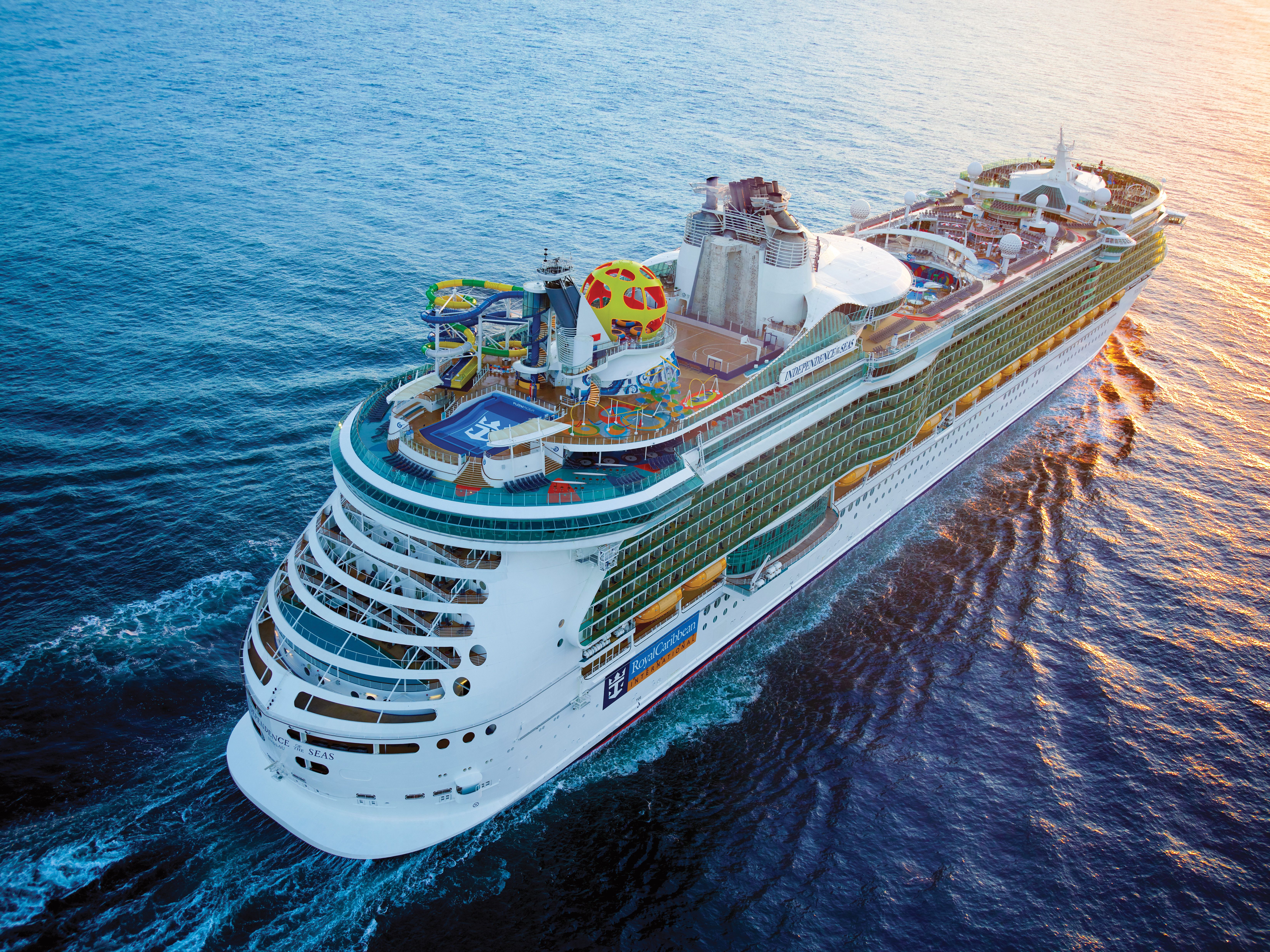 Royal Caribbean’s Independence of the Seas sailing at sunrise, featuring water slides, sports court, and family-friendly deck activities.