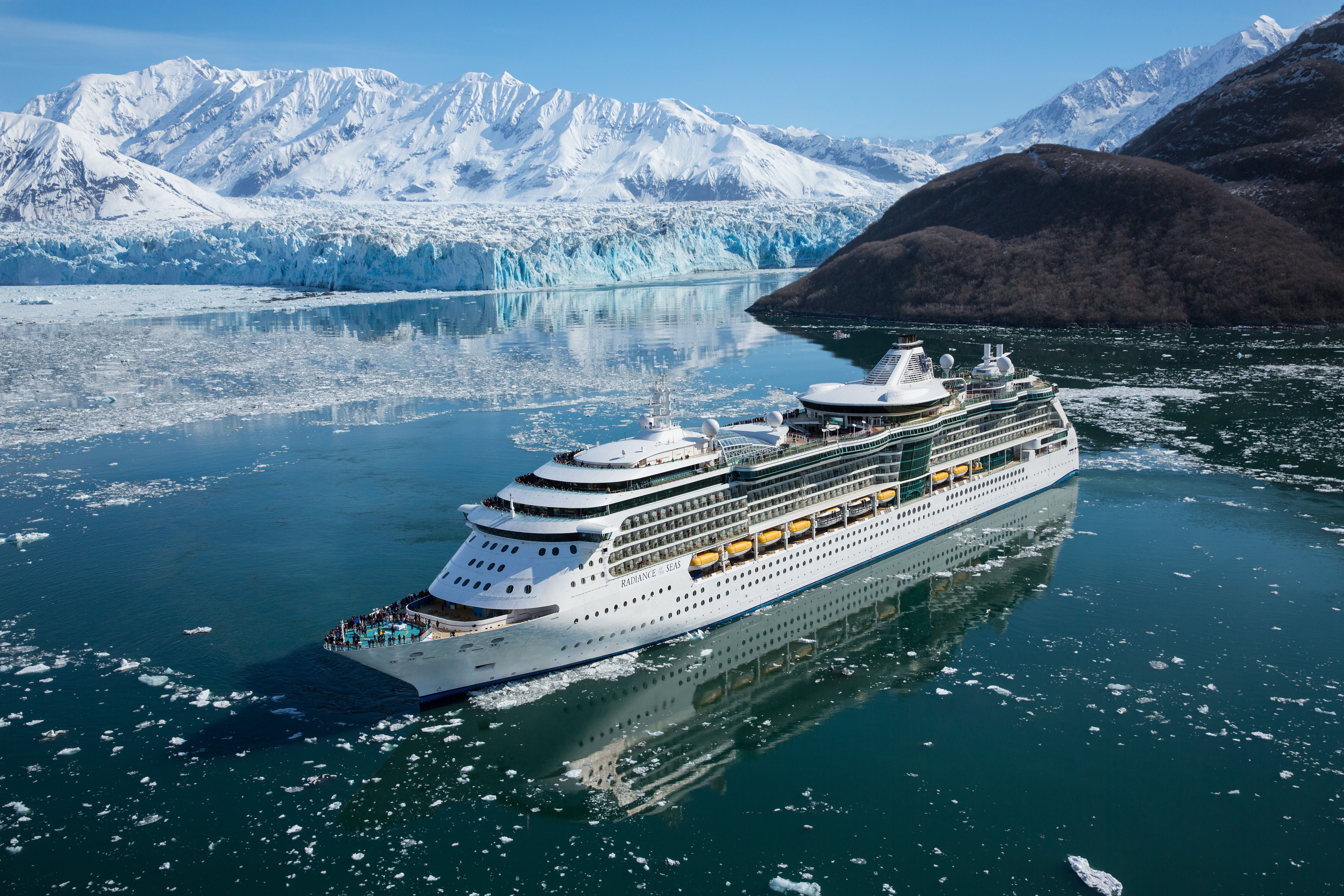 Royal Caribbean’s Radiance of the Seas sailing through icy Alaskan waters with glacier views and snow-covered mountains.