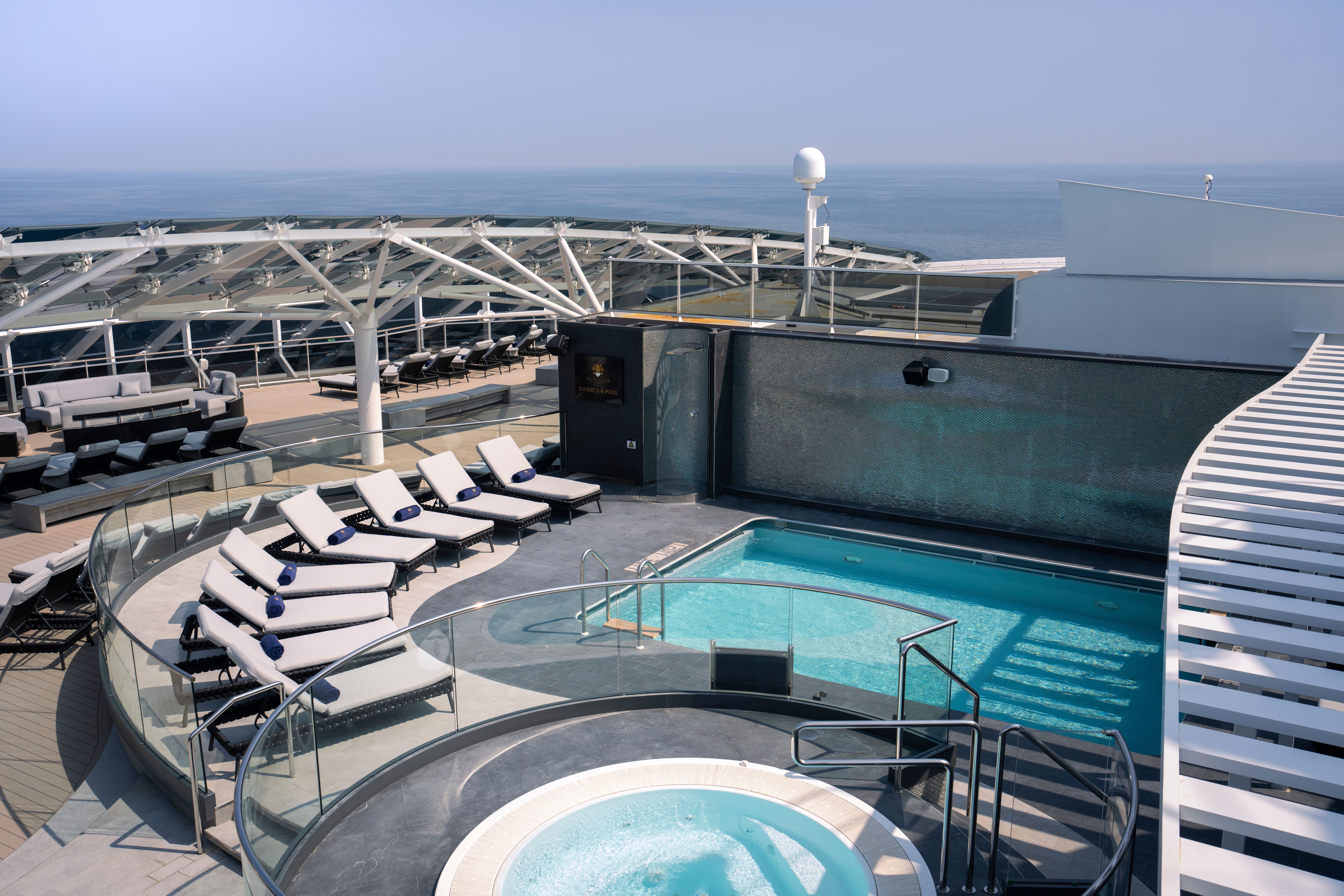 Exclusive MSC Yacht Club sundeck with private pool, whirlpool, cushioned loungers, and ocean views beneath a sleek canopy structure.