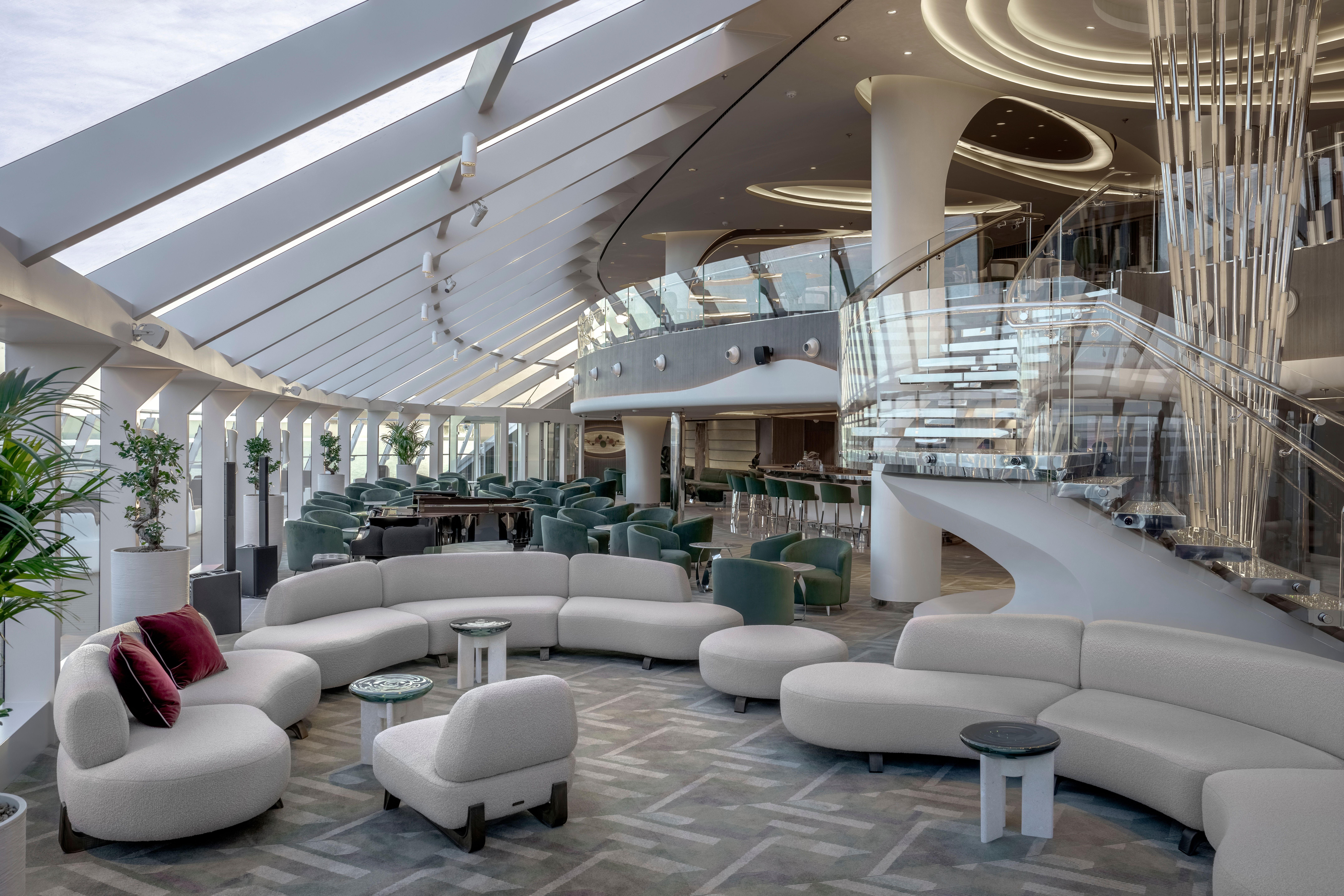 Sophisticated Top Sail Lounge on MSC Yacht Club with panoramic windows, plush seating, crystal staircase, and piano area in a light-filled luxury setting.