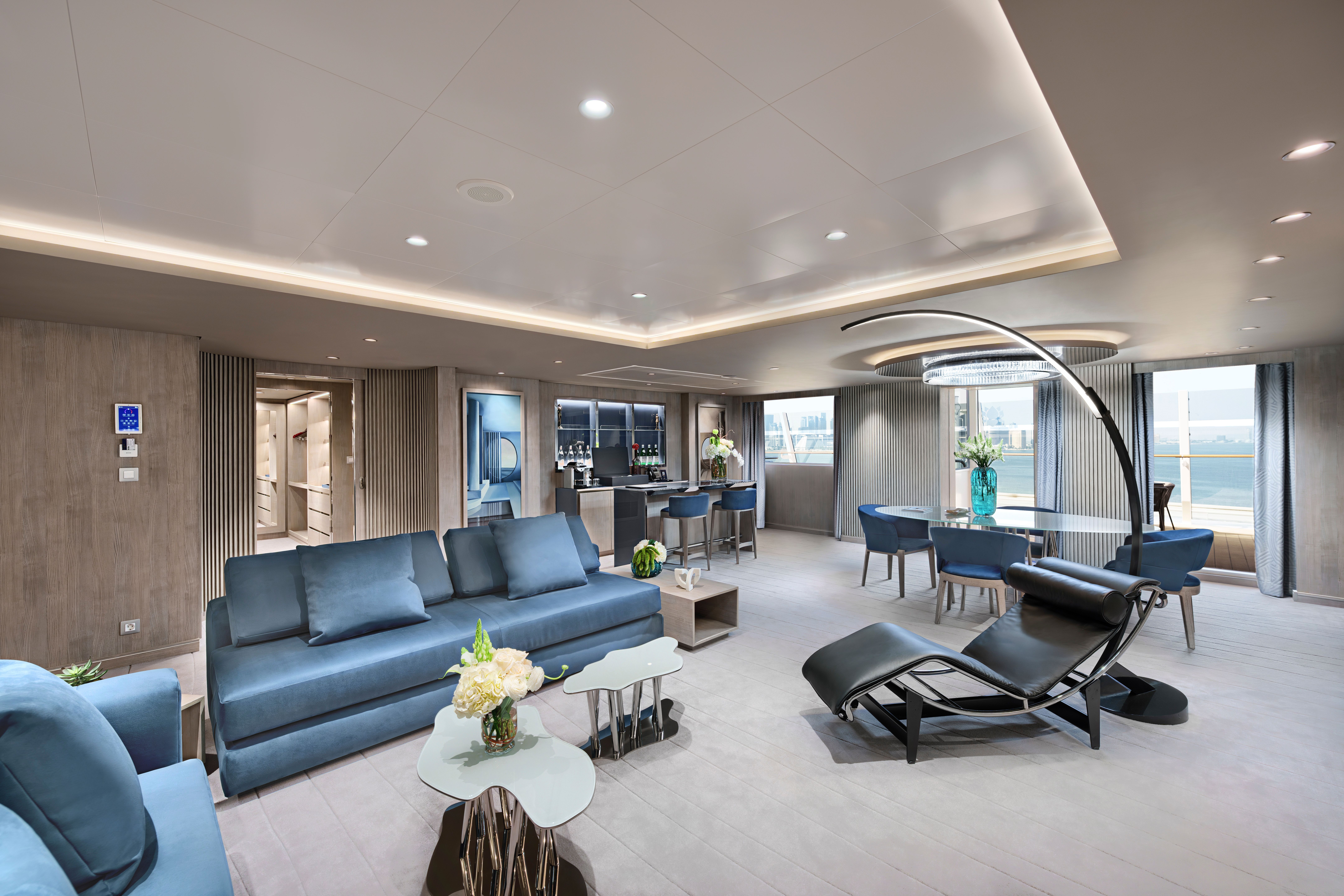 Lavish MSC Yacht Club Owner’s Suite featuring spacious living and dining areas, floor-to-ceiling windows, private bar, and modern designer furnishings.