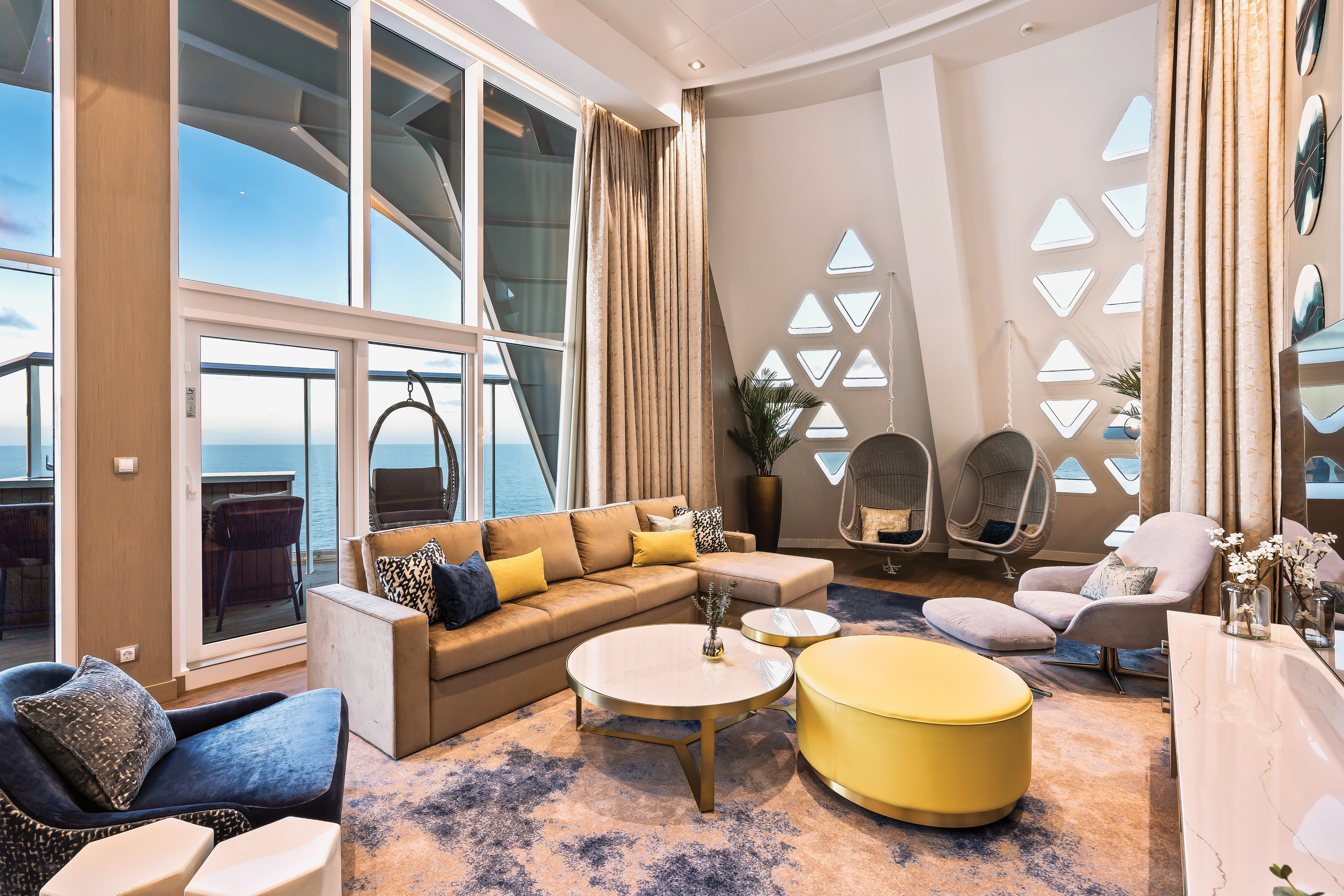 Ultra-luxurious Royal Loft Suite aboard Royal Caribbean featuring a double-height living room, oceanview balcony, designer furnishings, and glass staircase.