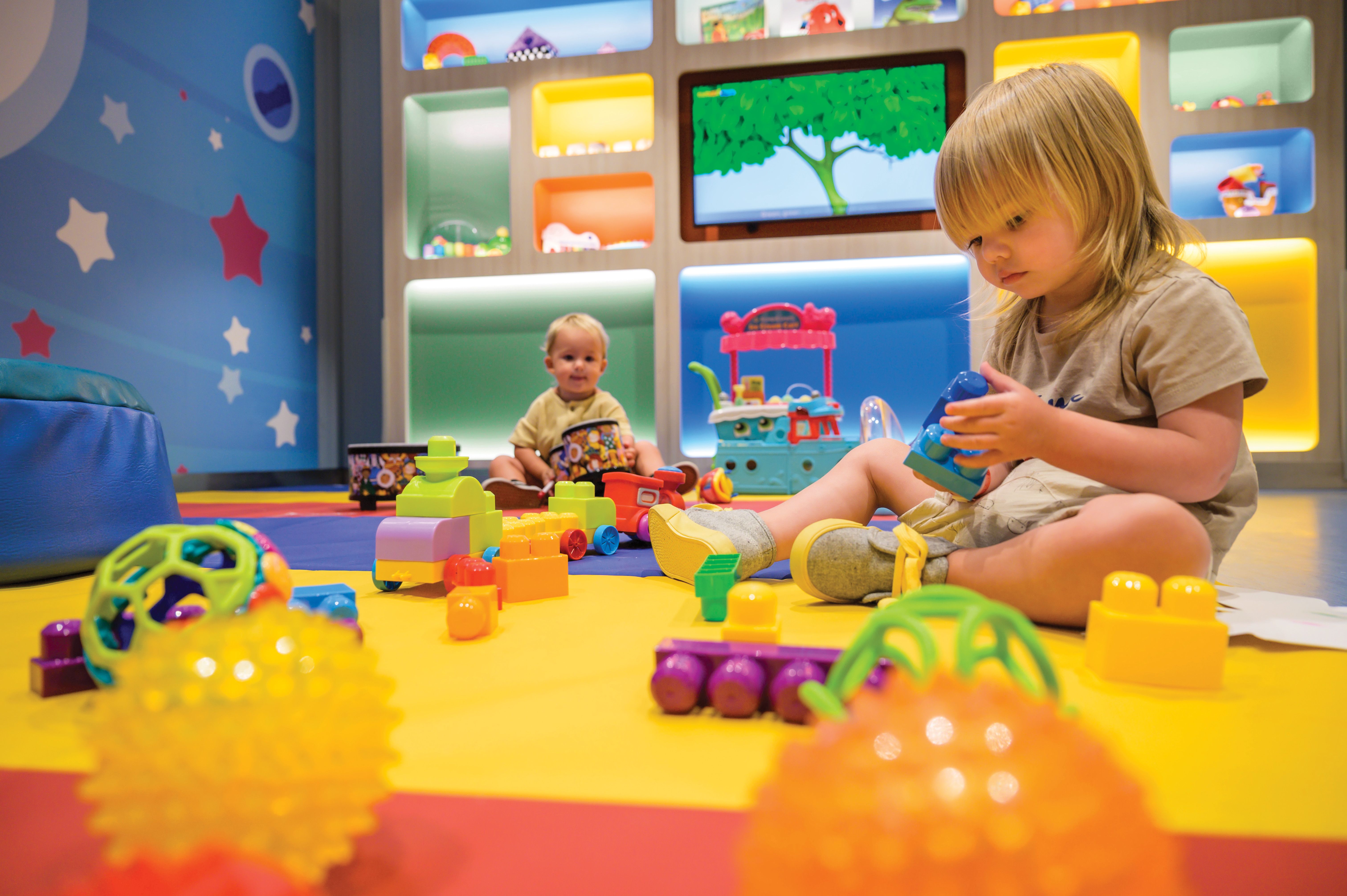 Royal Caribbean’s Adventure Ocean Babies playroom with toddlers engaged in colorful toys and soft play under supervised, age-appropriate enrichment.