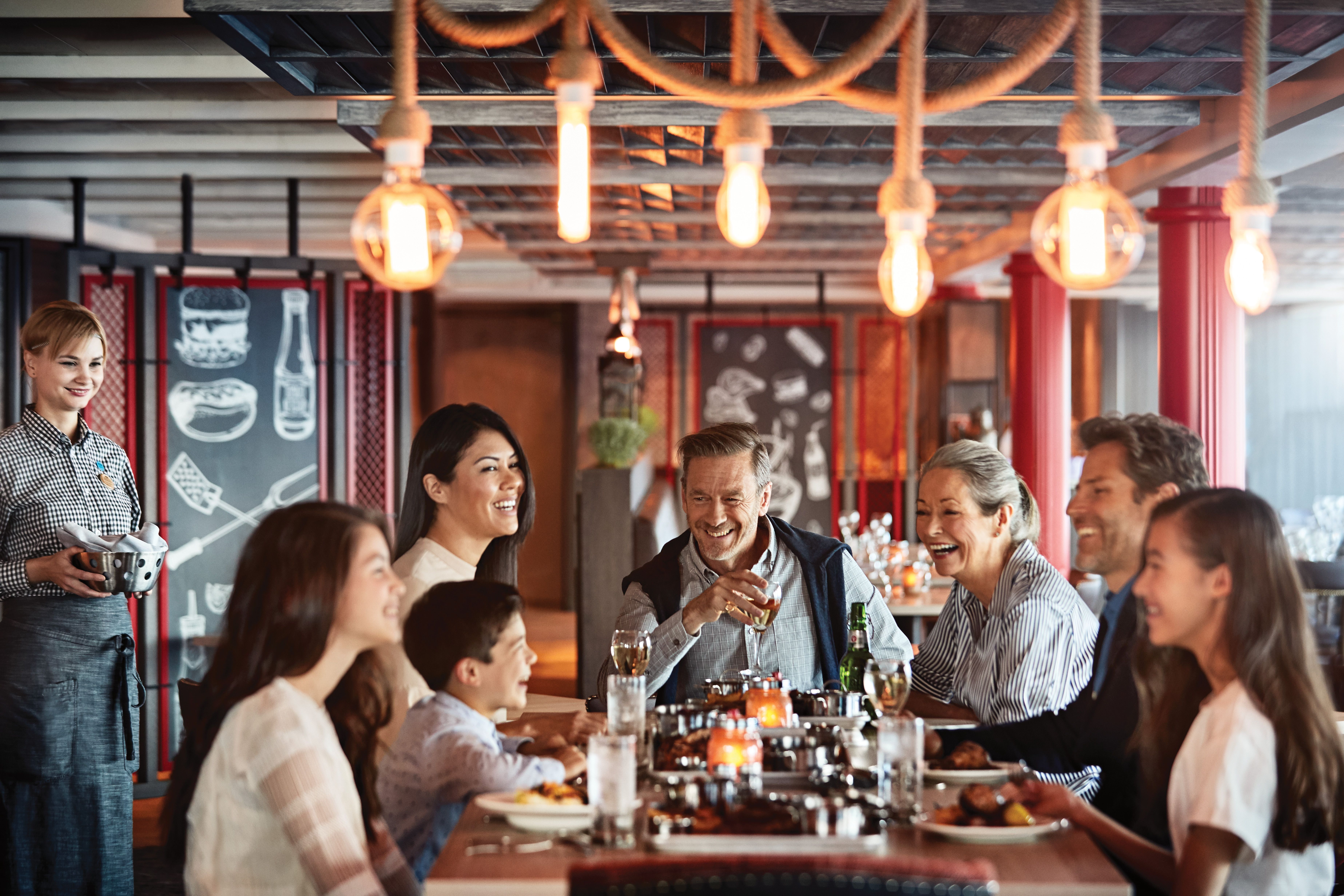 Multi-generational family enjoying dinner together at a Princess Cruises restaurant, with warm lighting and attentive service onboard.
