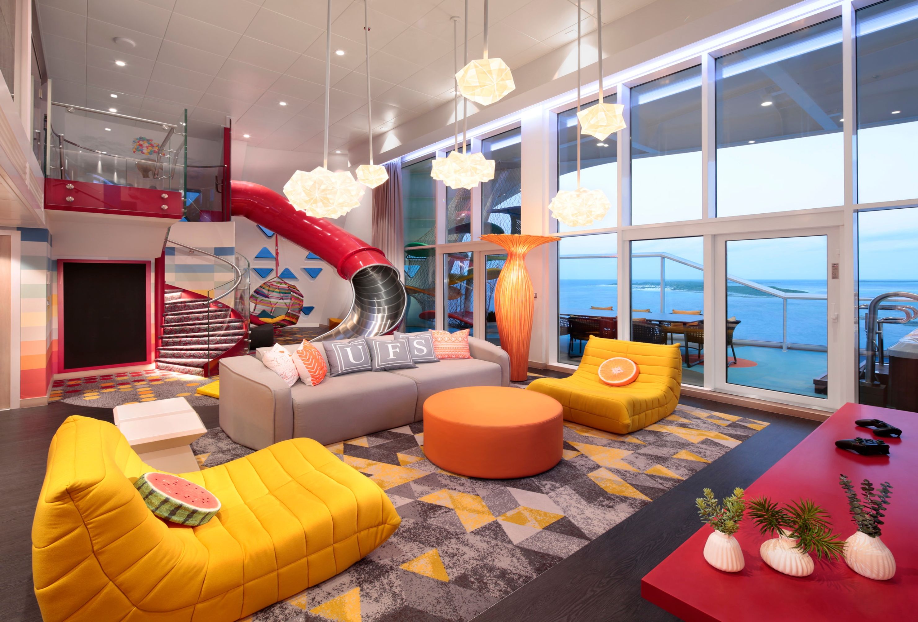 Ultimate Family Suite on Royal Caribbean with in-room slide, vibrant lounge seating, game zone, and private balcony ocean views.