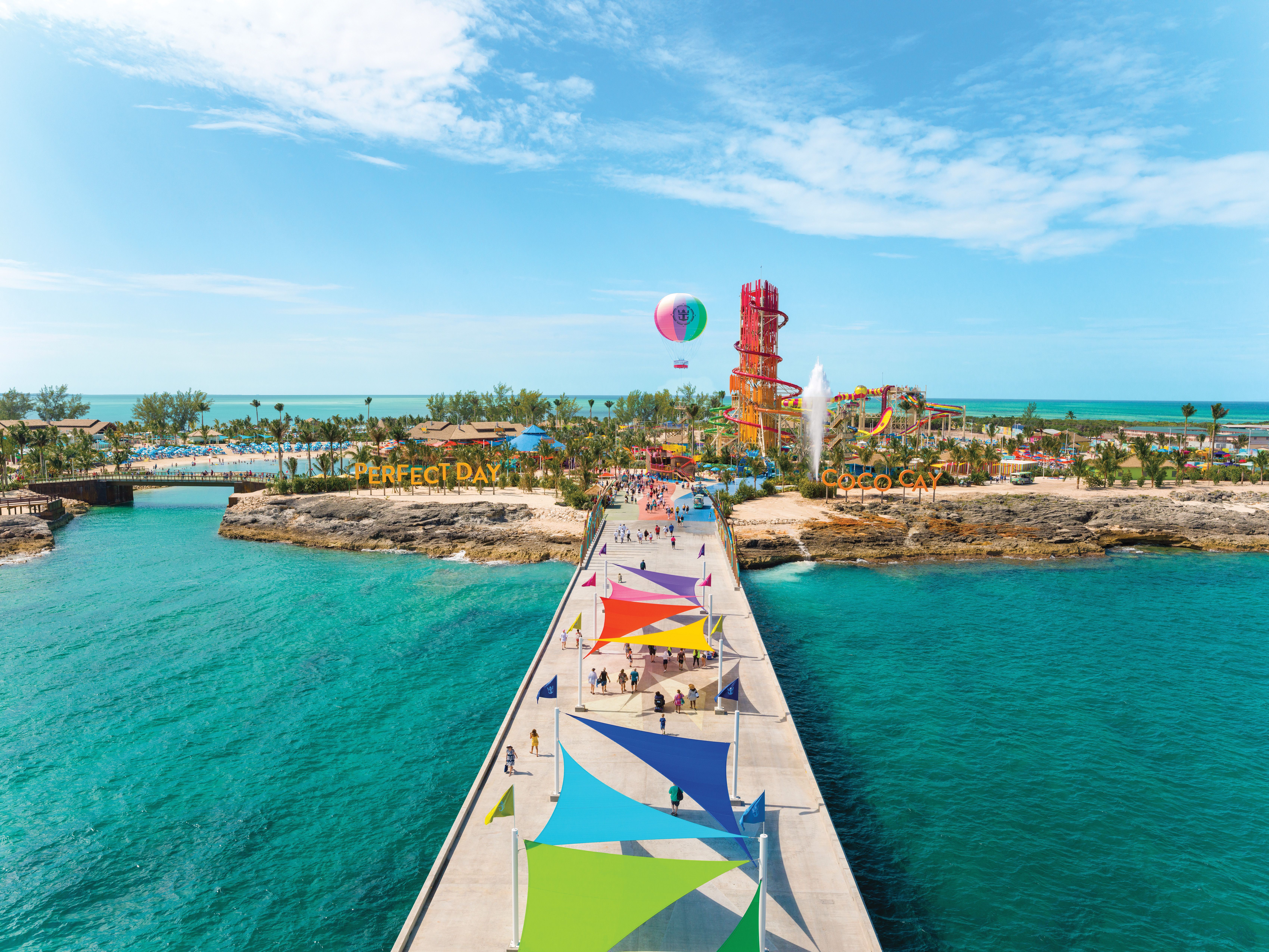 Pier entrance to Perfect Day at CocoCay with colorful shade sails, waterpark slides, and helium balloon soaring over Royal Caribbean’s private island.