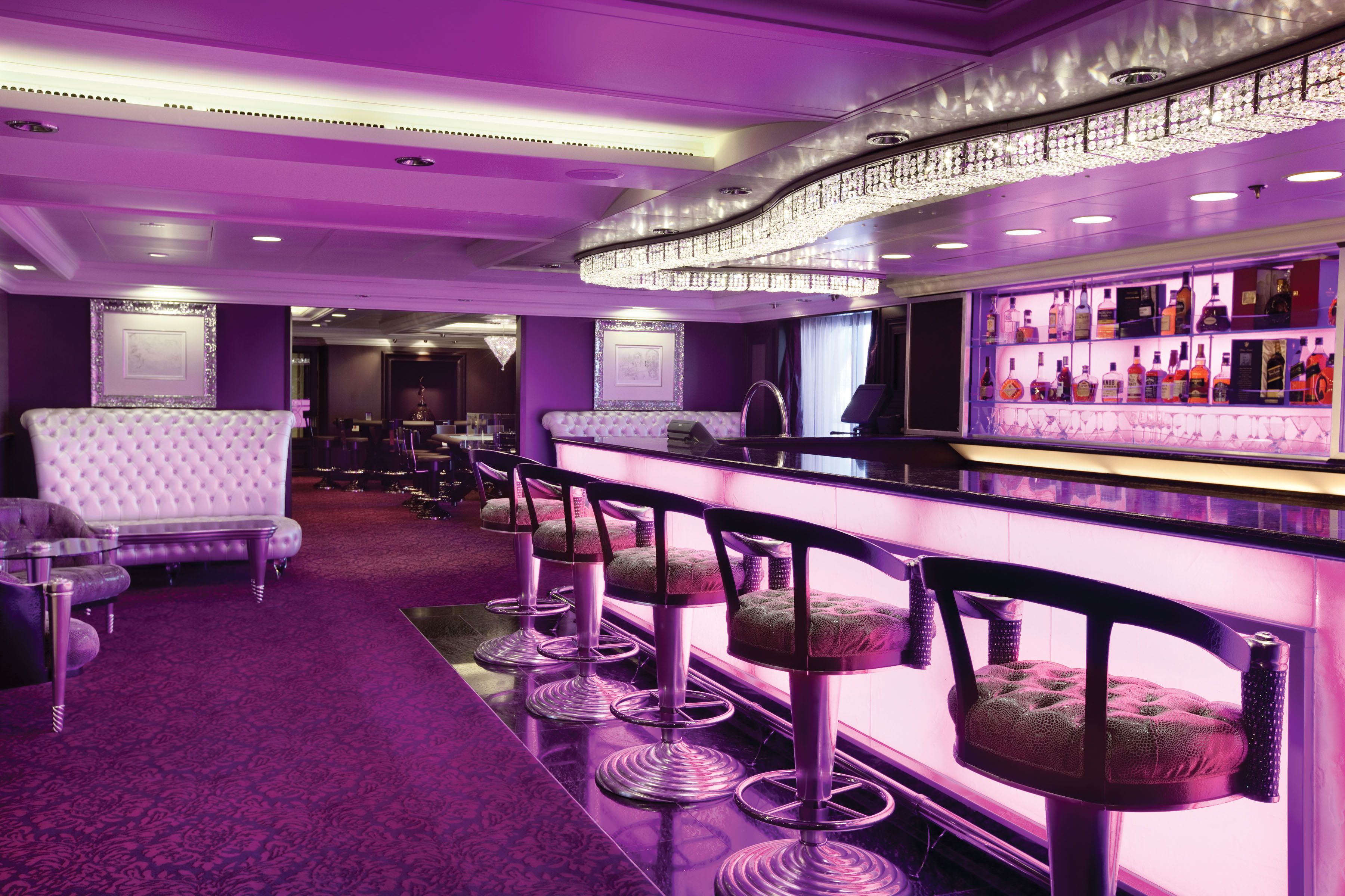 Oceania Riviera Casino Bar with plush seating, illuminated counter, and elegant purple décor for a vibrant nightlife atmosphere onboard.