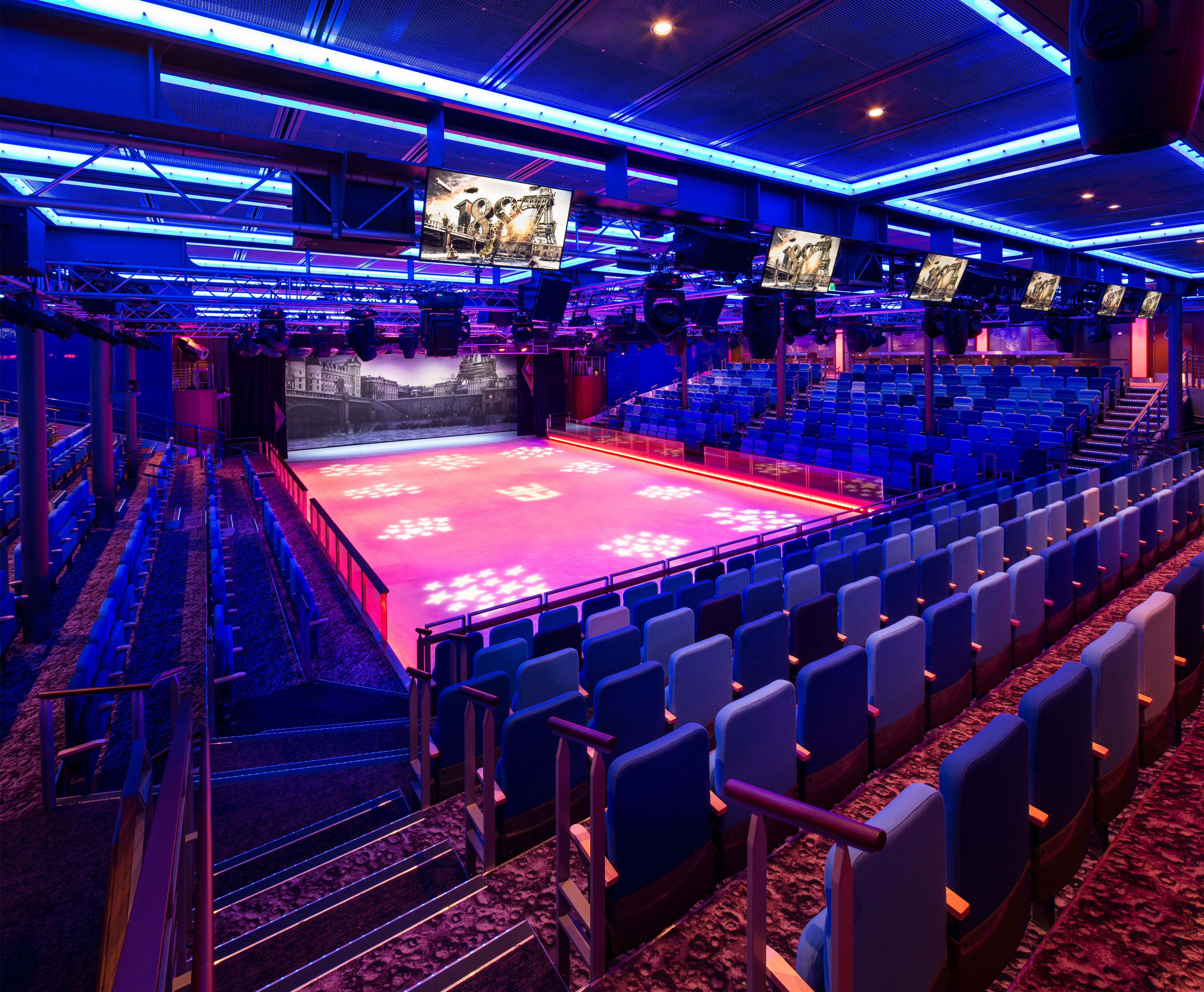 Studio B on Adventure of the Seas, a vibrant onboard ice-skating rink and entertainment venue with stadium seating and dramatic lighting for spectacular shows.