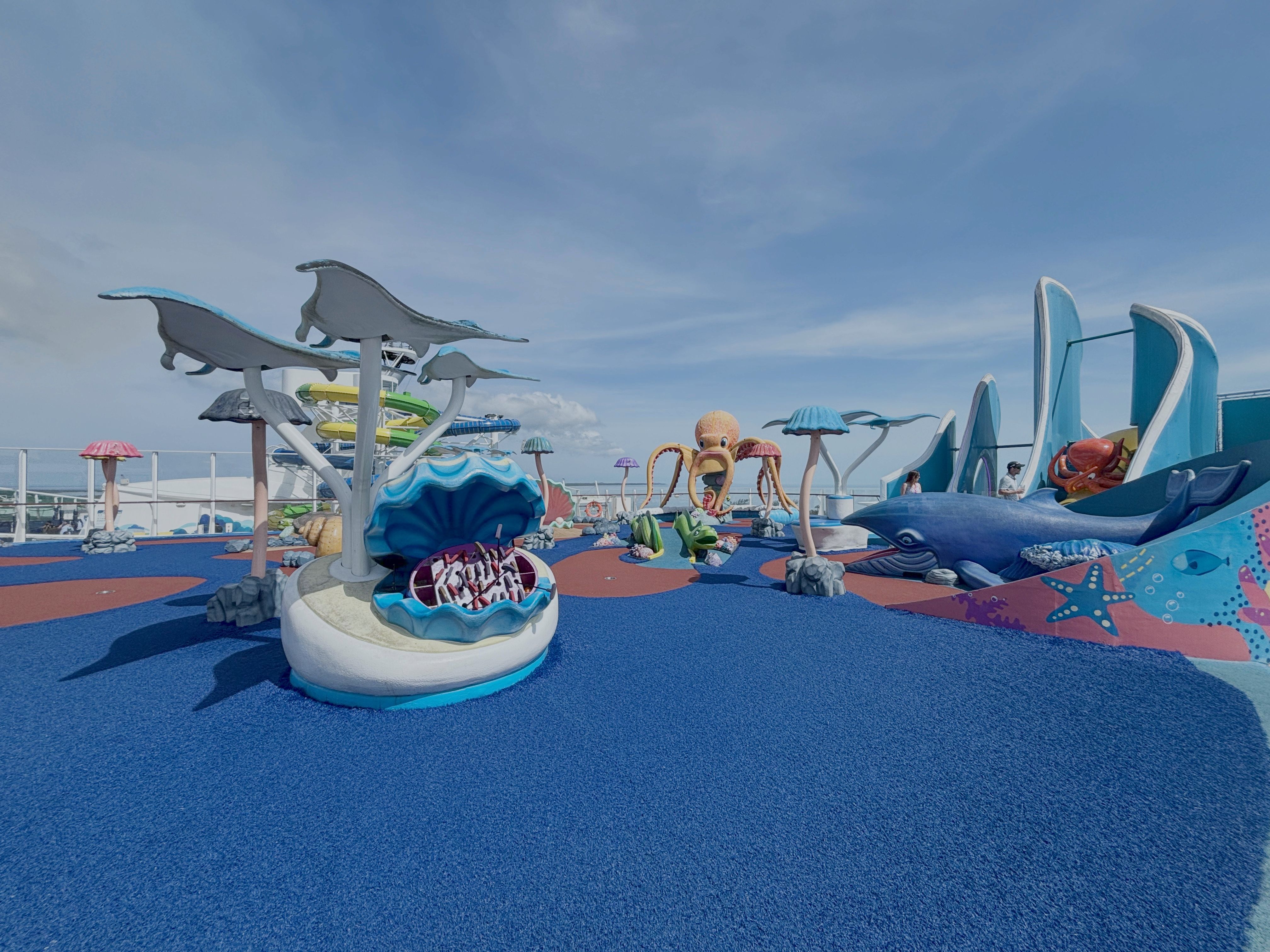 Colorful ocean-themed mini golf course on a cruise ship deck, featuring sea creature sculptures and playful underwater decor under a sunny sky.