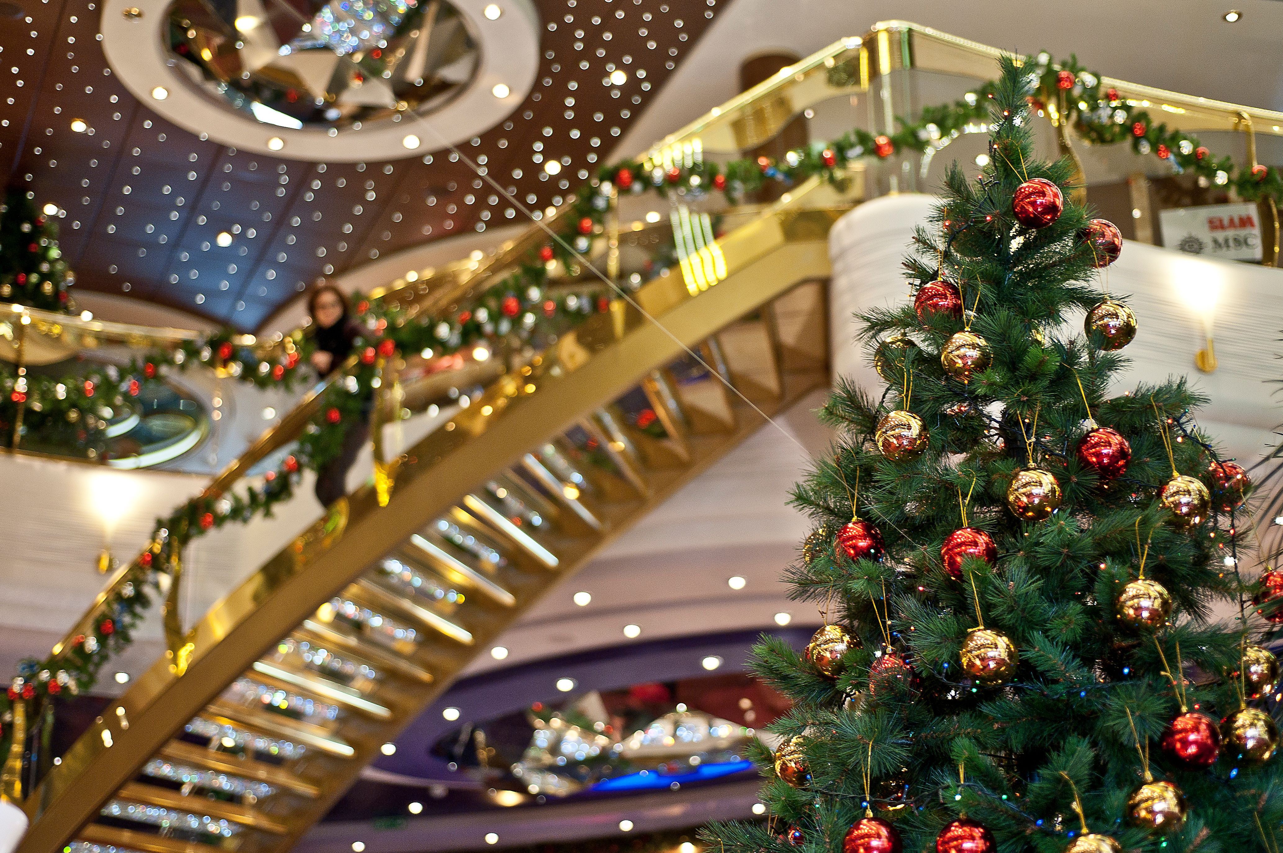 MSC Cruises grand staircase decked in gold and garland with a festive Christmas tree adorned in red and gold ornaments, creating a luxurious holiday ambiance.