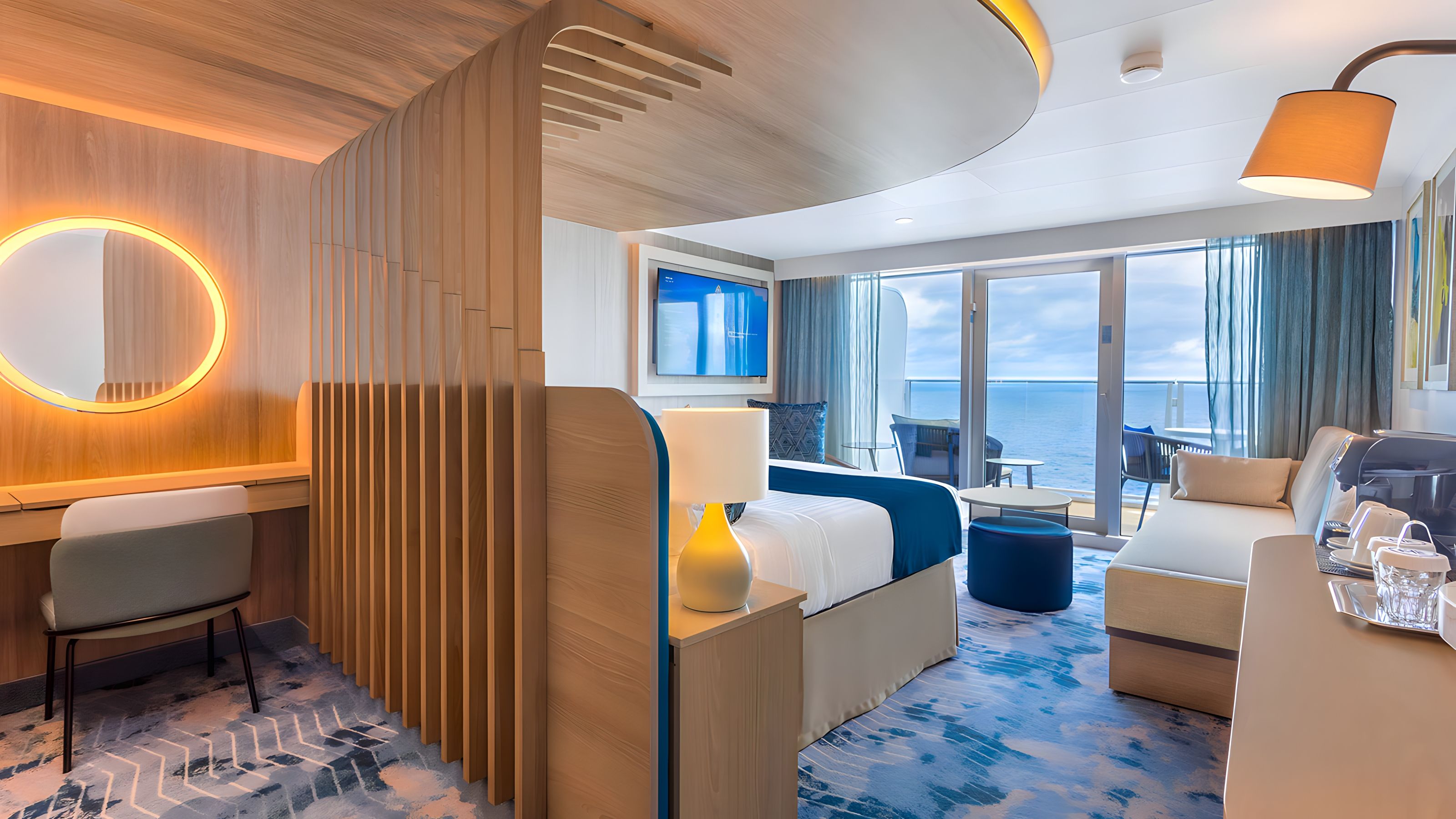 Sky Junior Suite featuring a plush king bed, stylish sofa, and sliding doors to a private ocean-view balcony.
