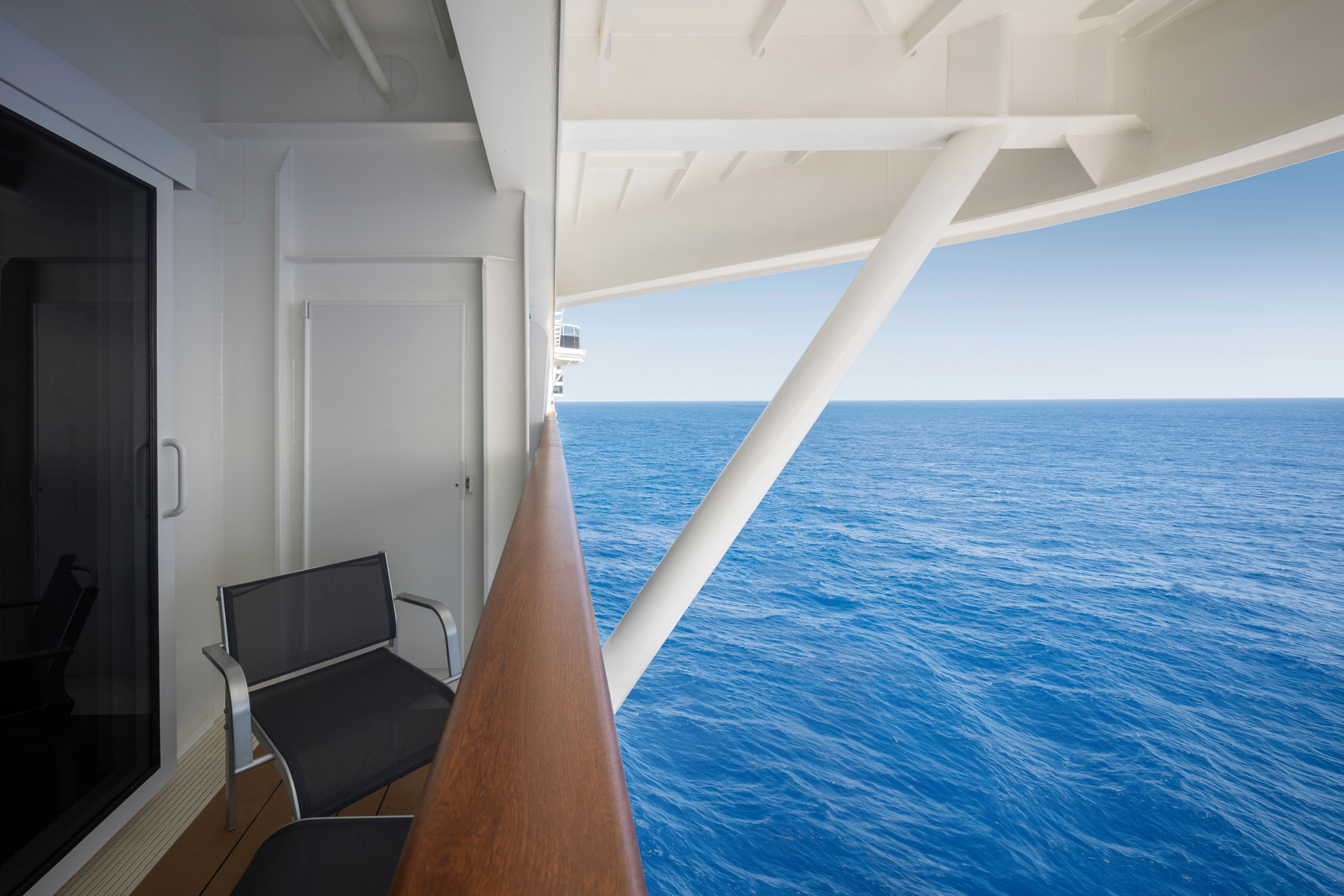 Private balcony on MSC World America with chairs and partial ocean view, partially obstructed by ship structure but still offering fresh sea air.