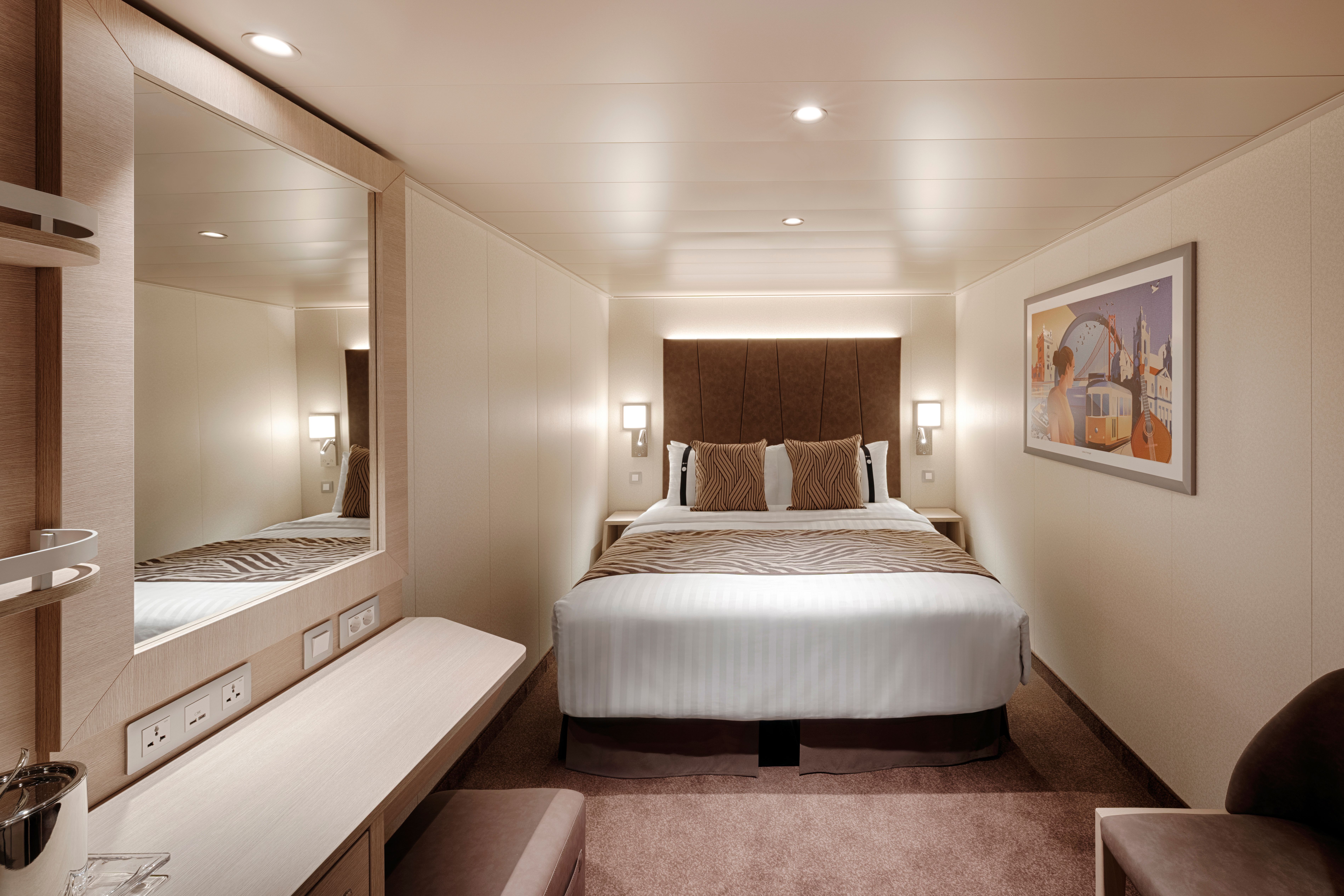 Deluxe Interior stateroom on MSC World America with queen bed, sleek desk, and soft lighting—ideal for comfort and relaxation during your cruise.