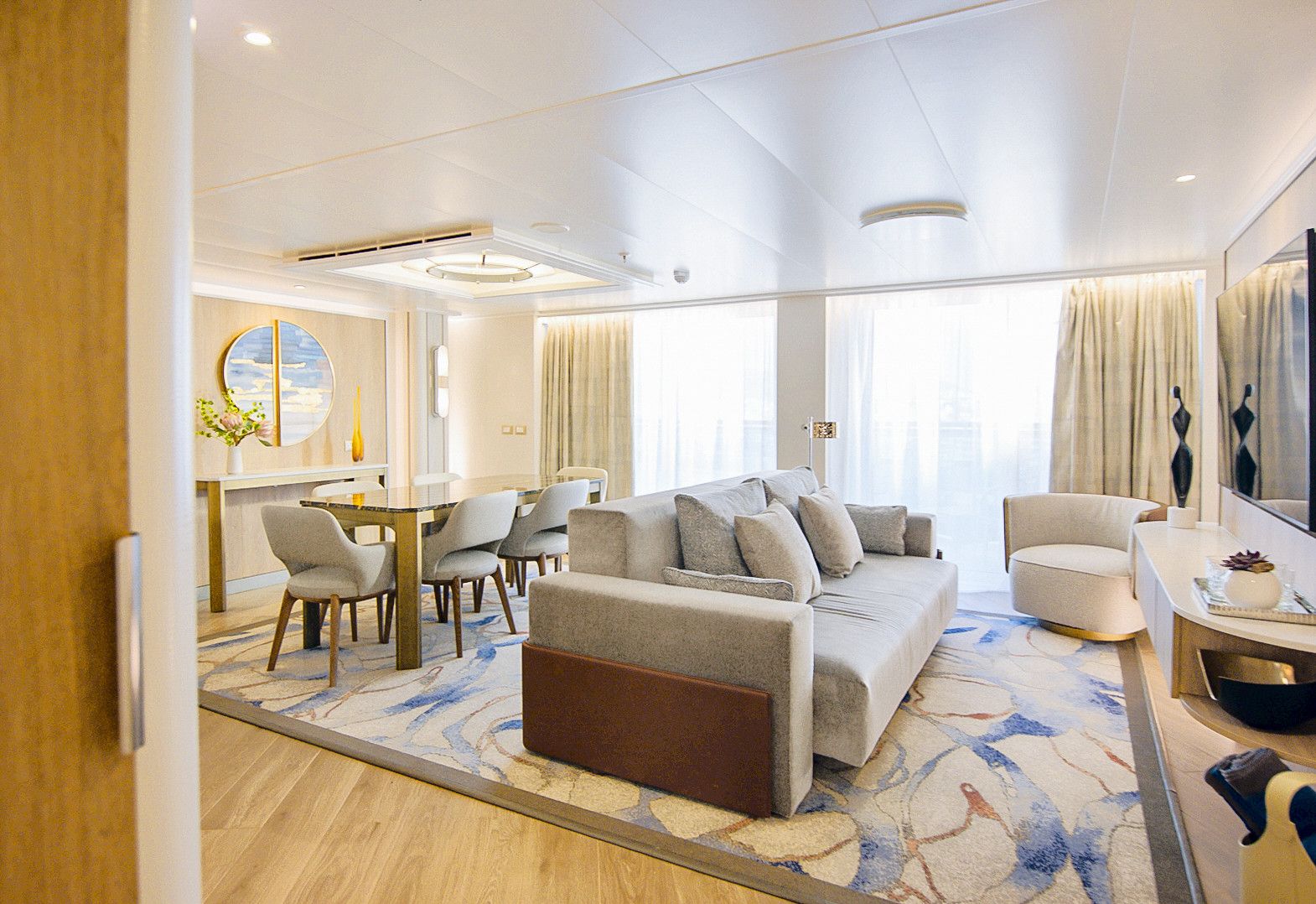 Princess Cruises Sky Suite living room with plush sofa, armchair, large windows and open-plan design offering spacious luxury cruise accommodations at sea.