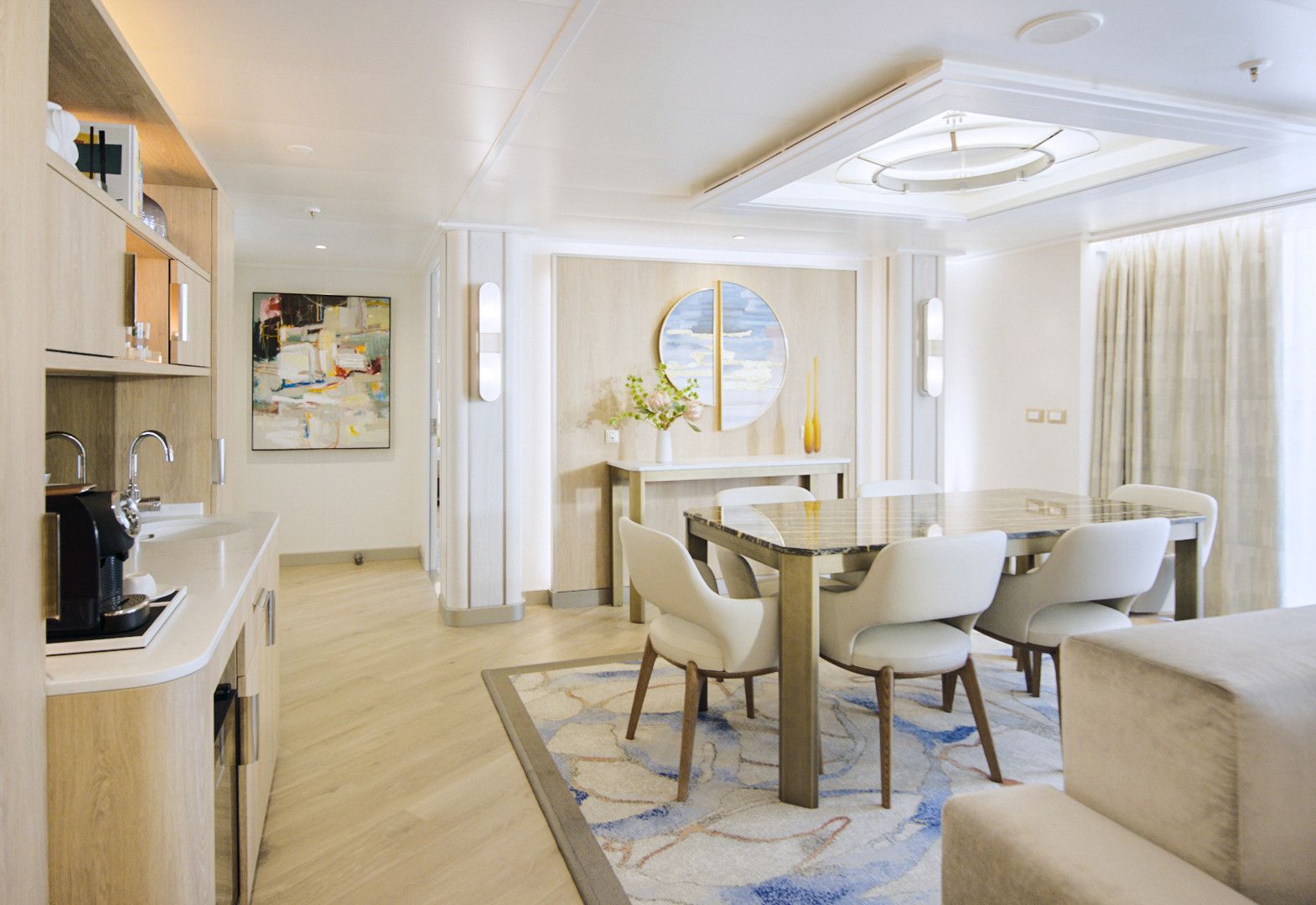 Princess Cruises Sky Suite dining area with marble-top table, four chairs, mini bar and stylish coastal décor in a premium luxury cruise suite.