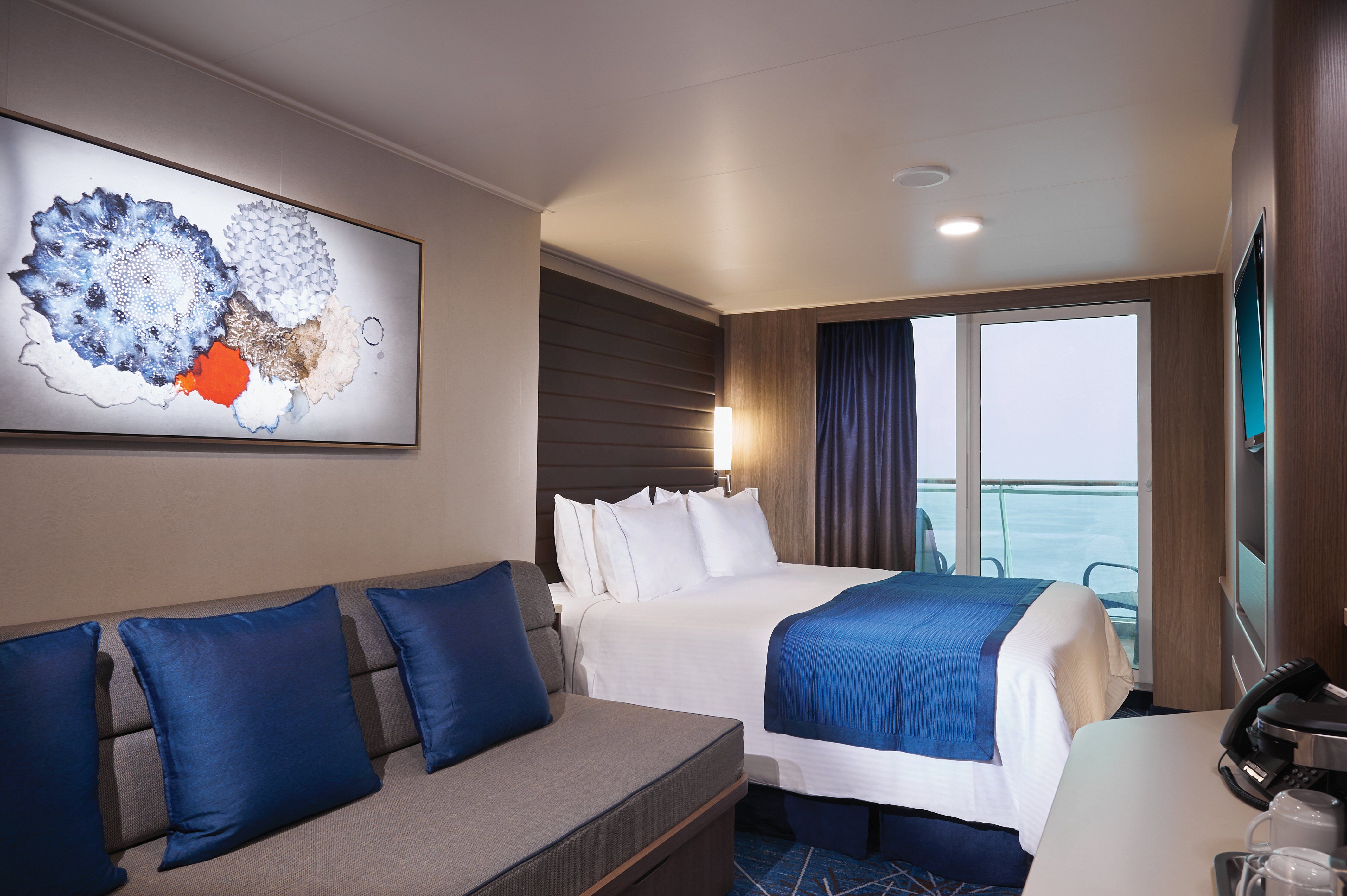 Norwegian Bliss Aft-Facing Balcony stateroom with queen bed, sofa and sliding doors opening to a private aft balcony with ocean views.