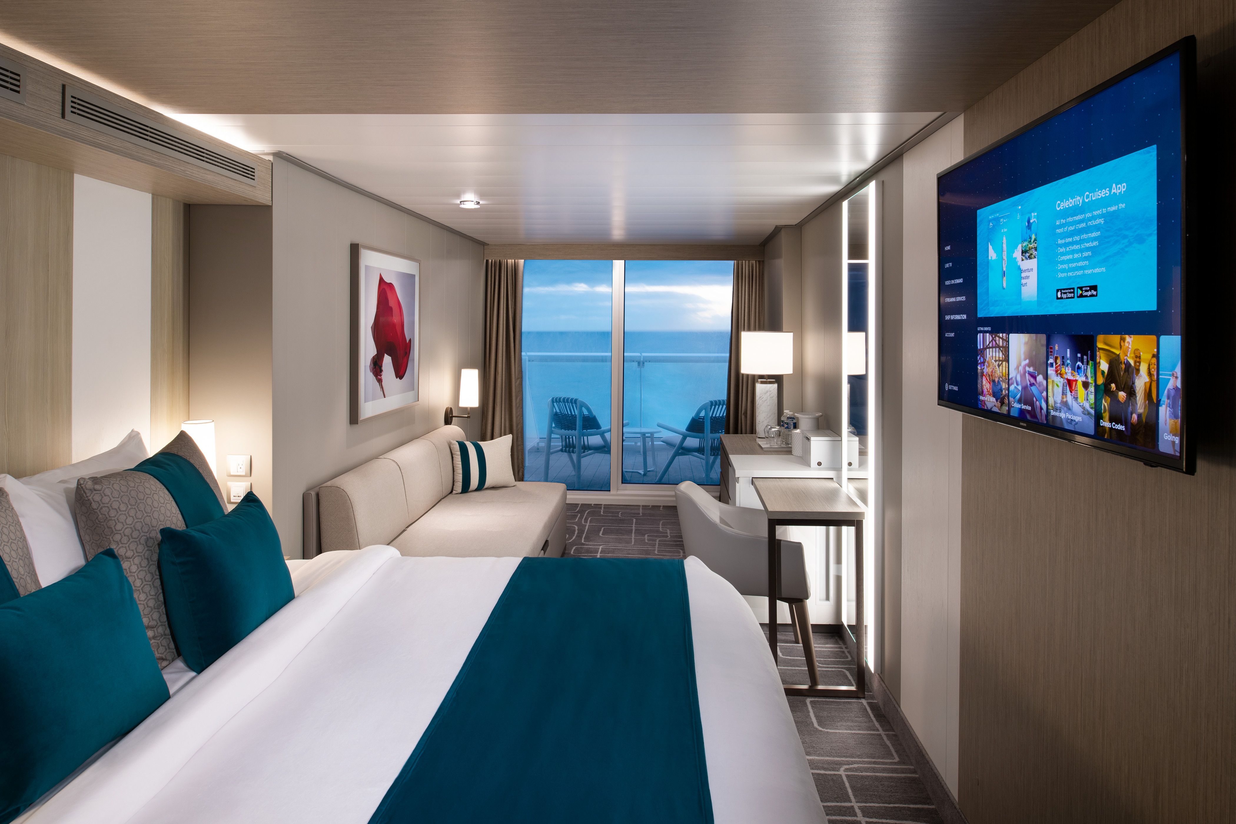 Celebrity Xcel Sunset Veranda stateroom with king-size bed, teal accents, modern sofa and floor-to-ceiling doors opening to ocean-view balcony