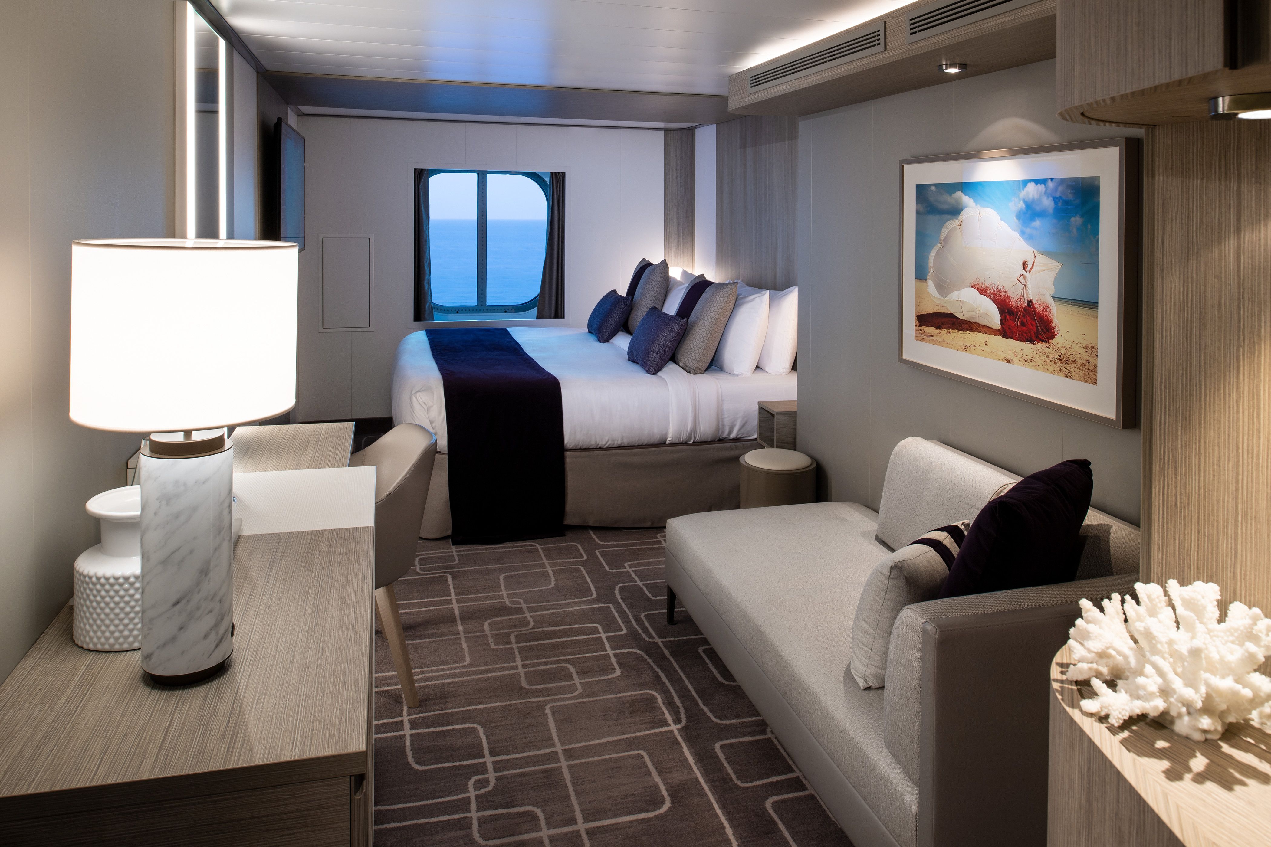 Celebrity Xcel Ocean View Stateroom with king-size bed, modern sofa, large oceanview window and contemporary cruise ship décor