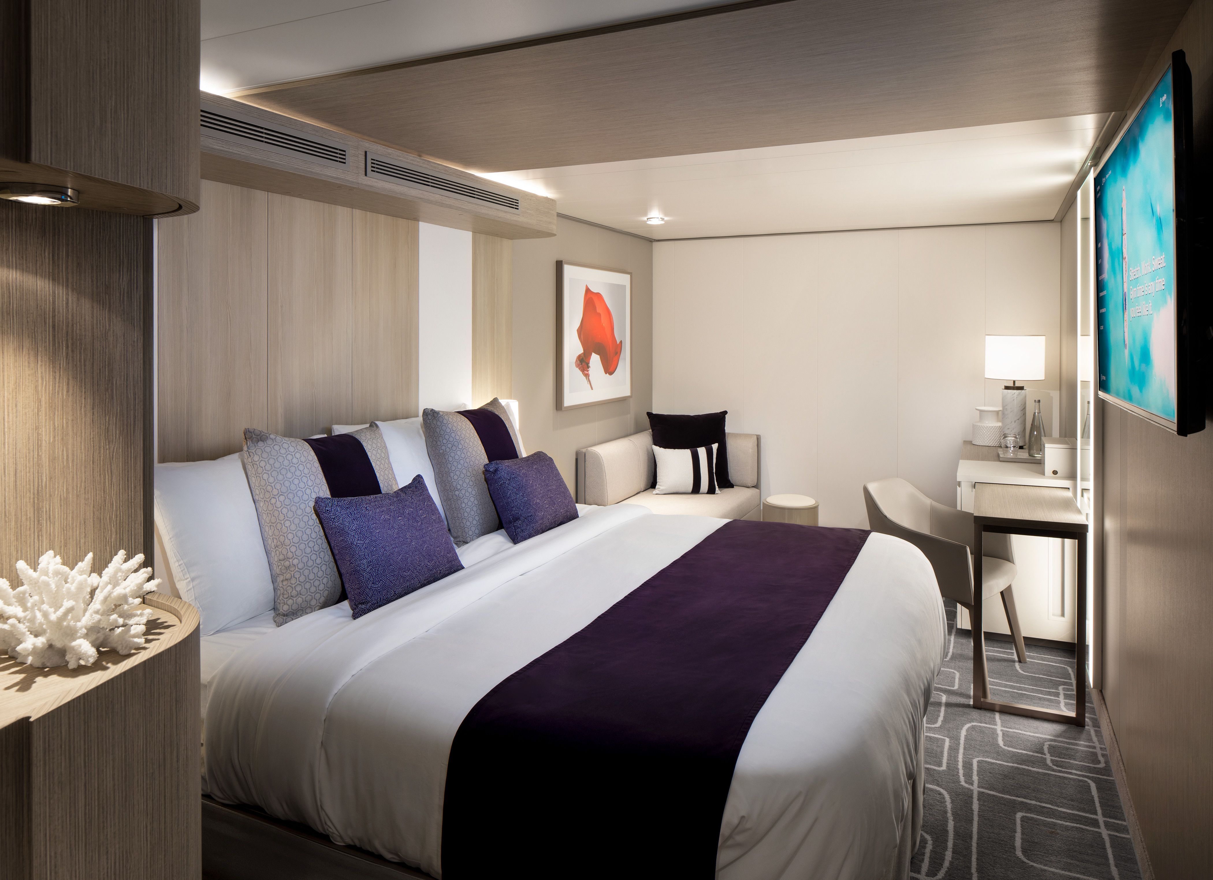 Celebrity Xcel Deluxe Inside Stateroom with king-size bed, modern sofa, vanity desk and contemporary cruise ship décor