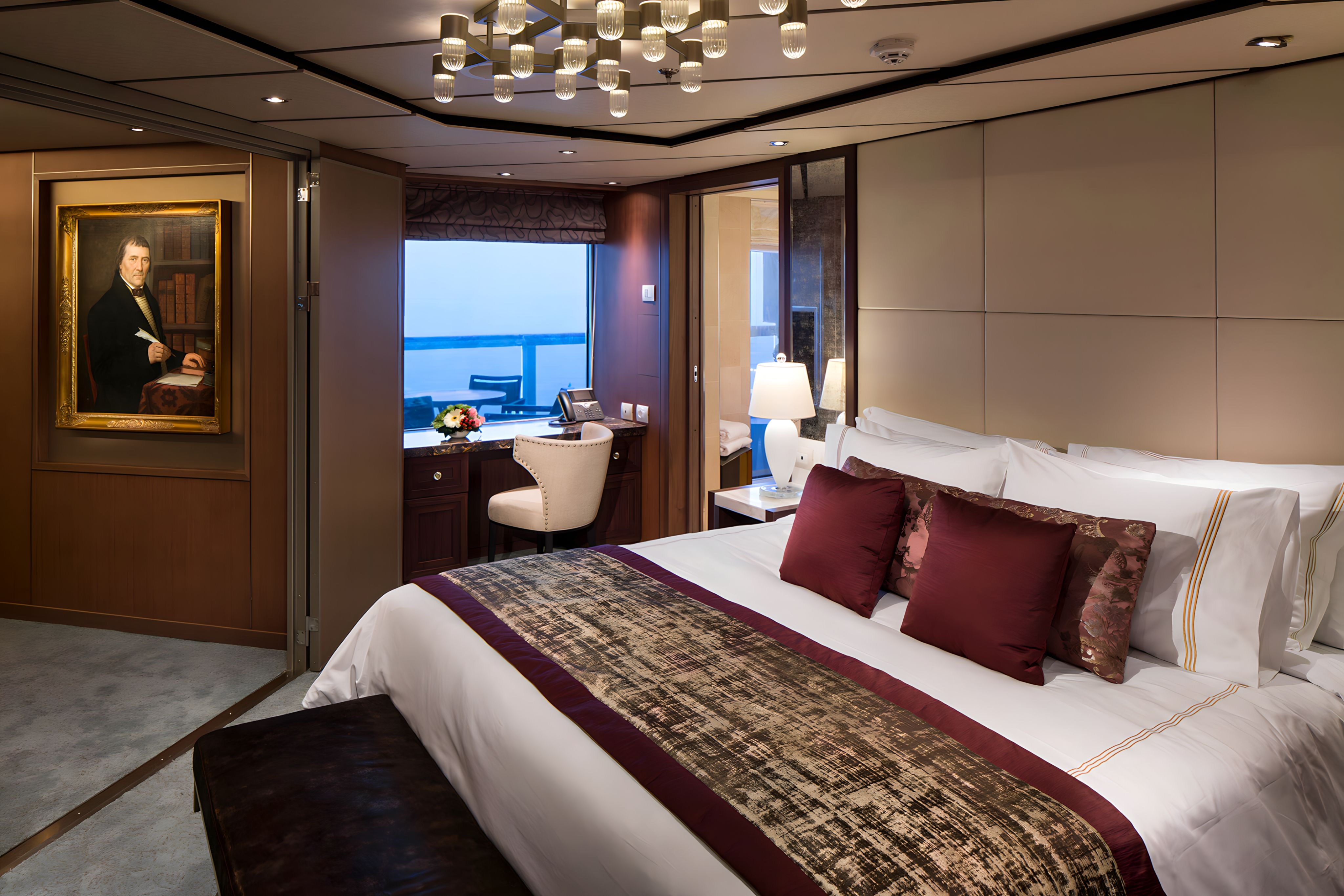 Holland America Line Nieuw Statendam Pinnacle Suite bedroom with king bed, elegant wood accents, writing desk and private balcony ocean views