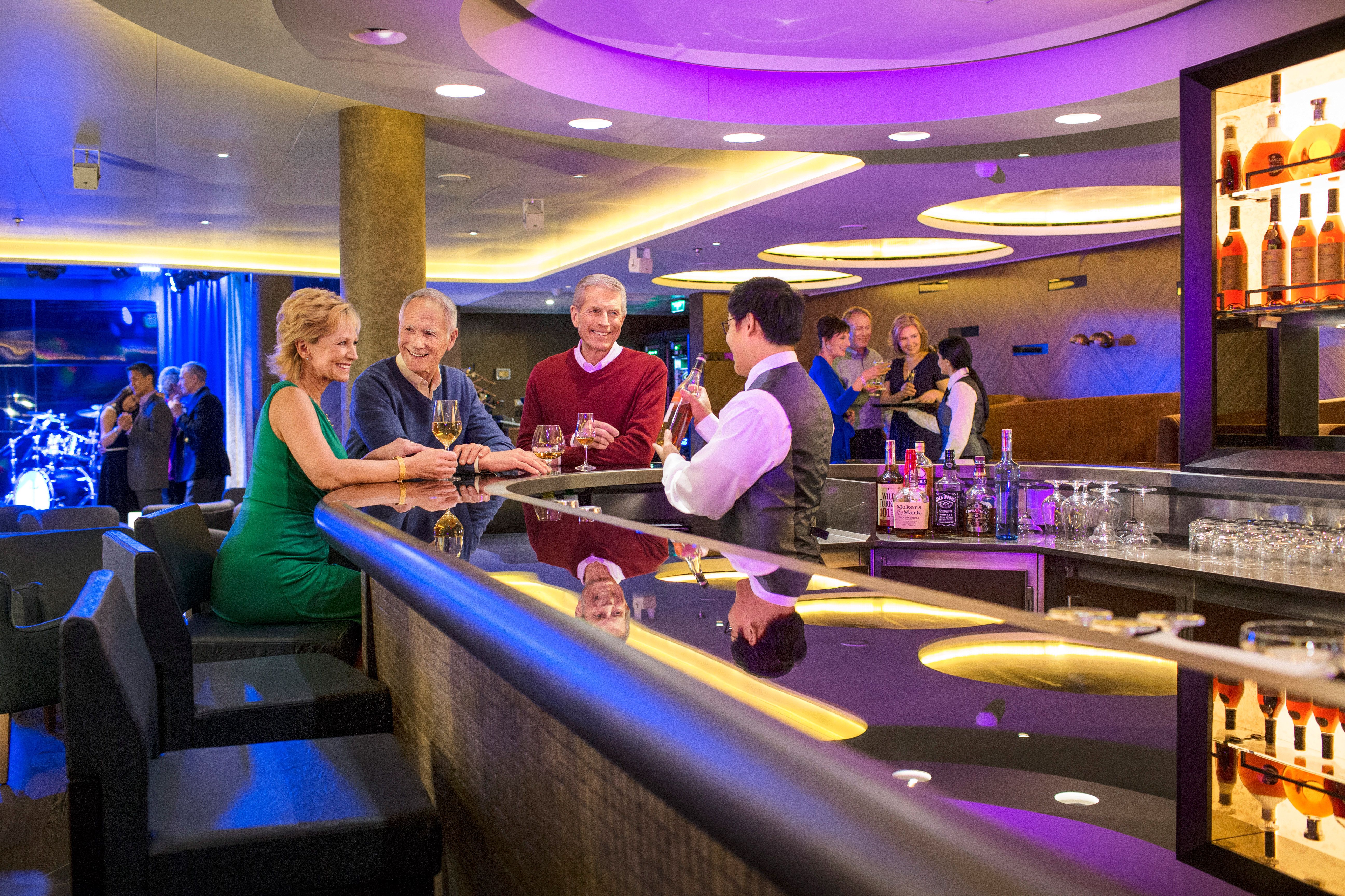 Viking Ocean Cruises Torshavn lounge bar with guests enjoying cocktails and live music, stylish onboard nightlife venue with bartender service and elegant cruise ship entertainment.