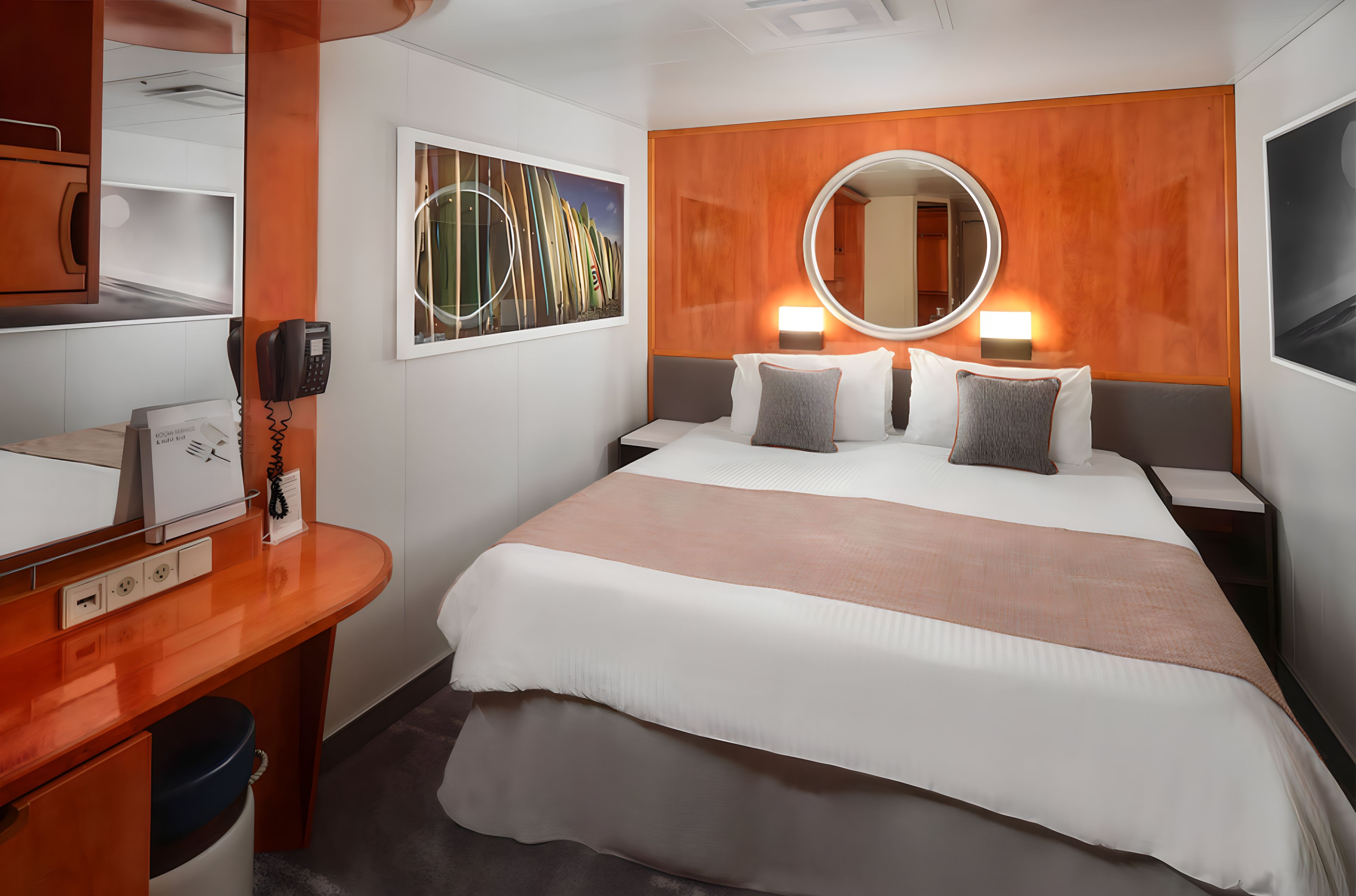 Inside stateroom on Norwegian Pride of America featuring queen bed, vanity desk, wall art, and modern interior cruise cabin design.