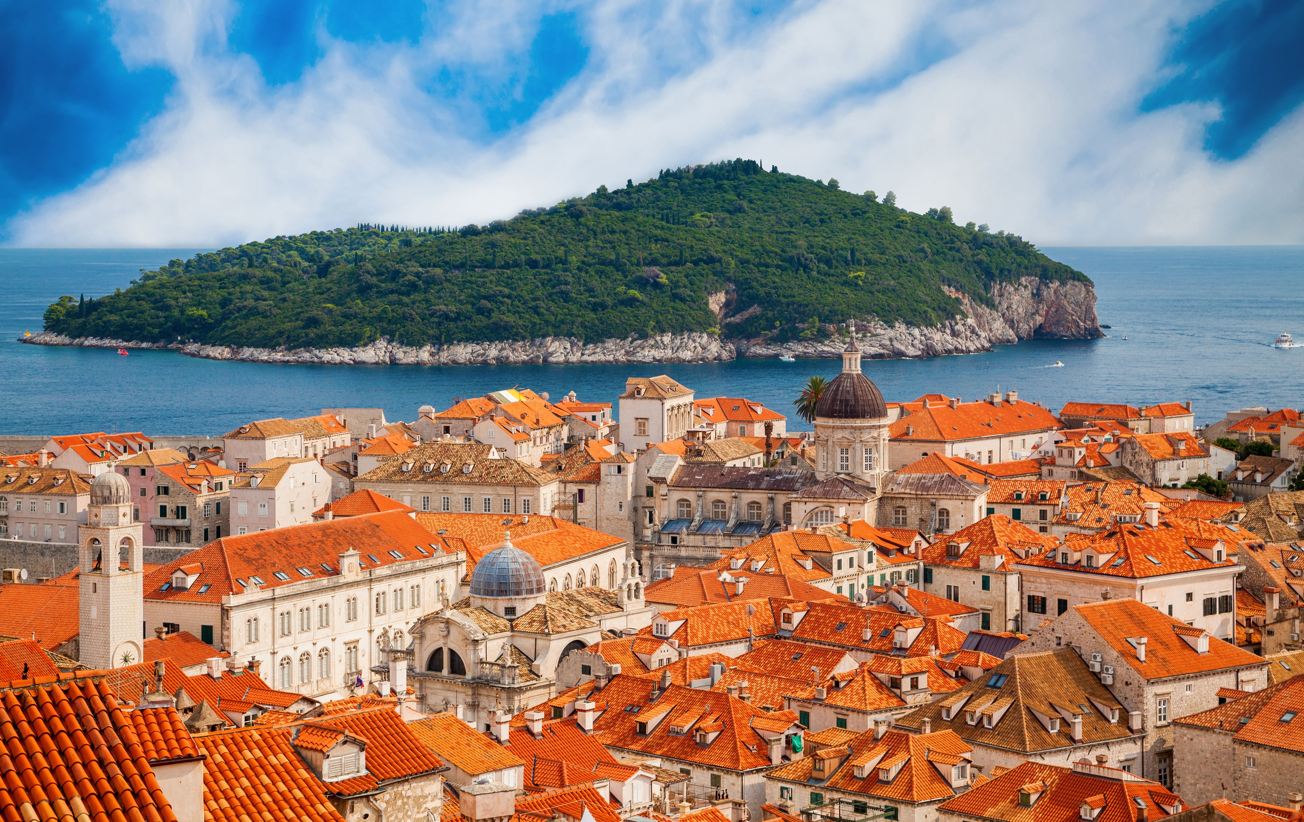 Dubrovnik Old Town red-tiled rooftops with Baroque church domes, Adriatic Sea views, and Lokrum Island in background, Croatia cruise destination scenic cityscape