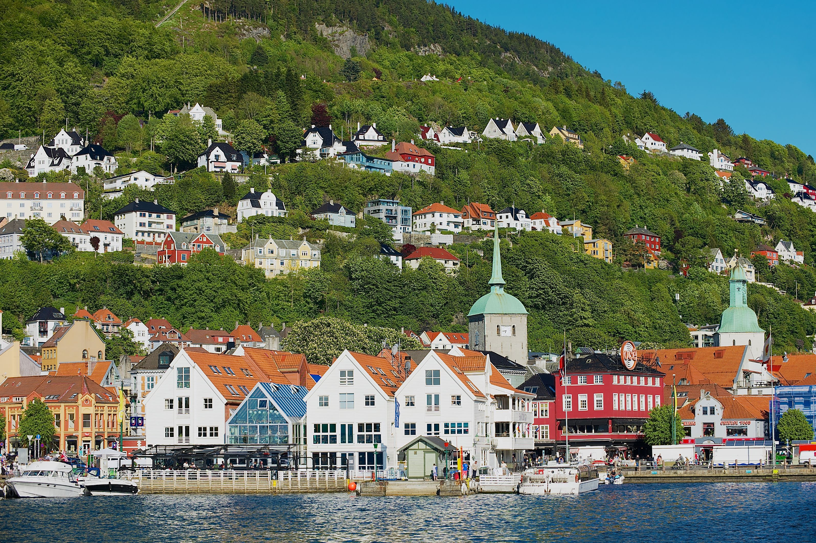 Bergen Norway waterfront with colorful Bryggen-style houses, harbor boats and hillside homes—popular cruise port with scenic fjord gateway and historic architecture