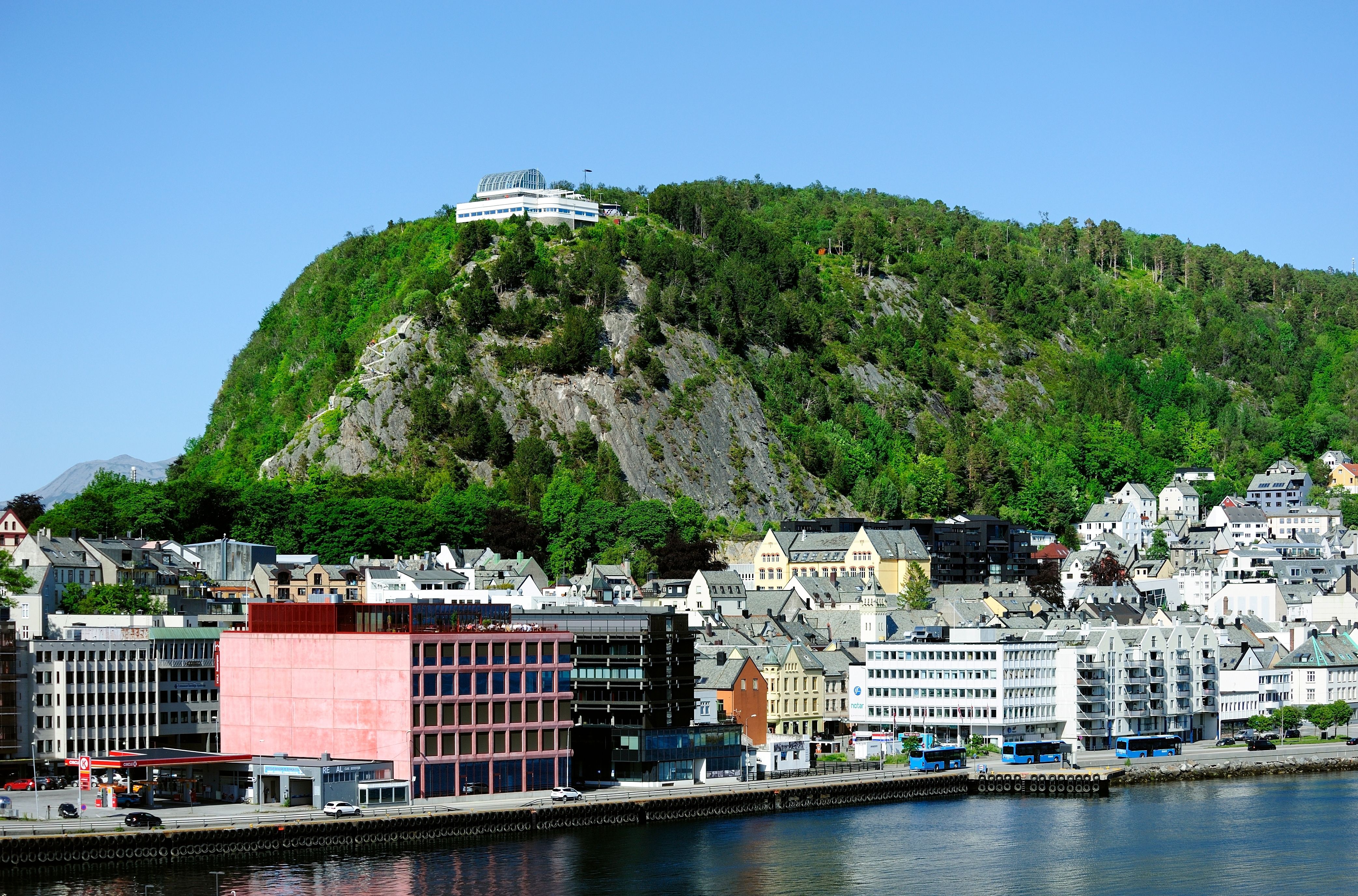 Alesund Norway waterfront and city skyline with Aksla viewpoint, harbor buildings and coastal mountains—popular cruise port with scenic fjord views and urban architecture