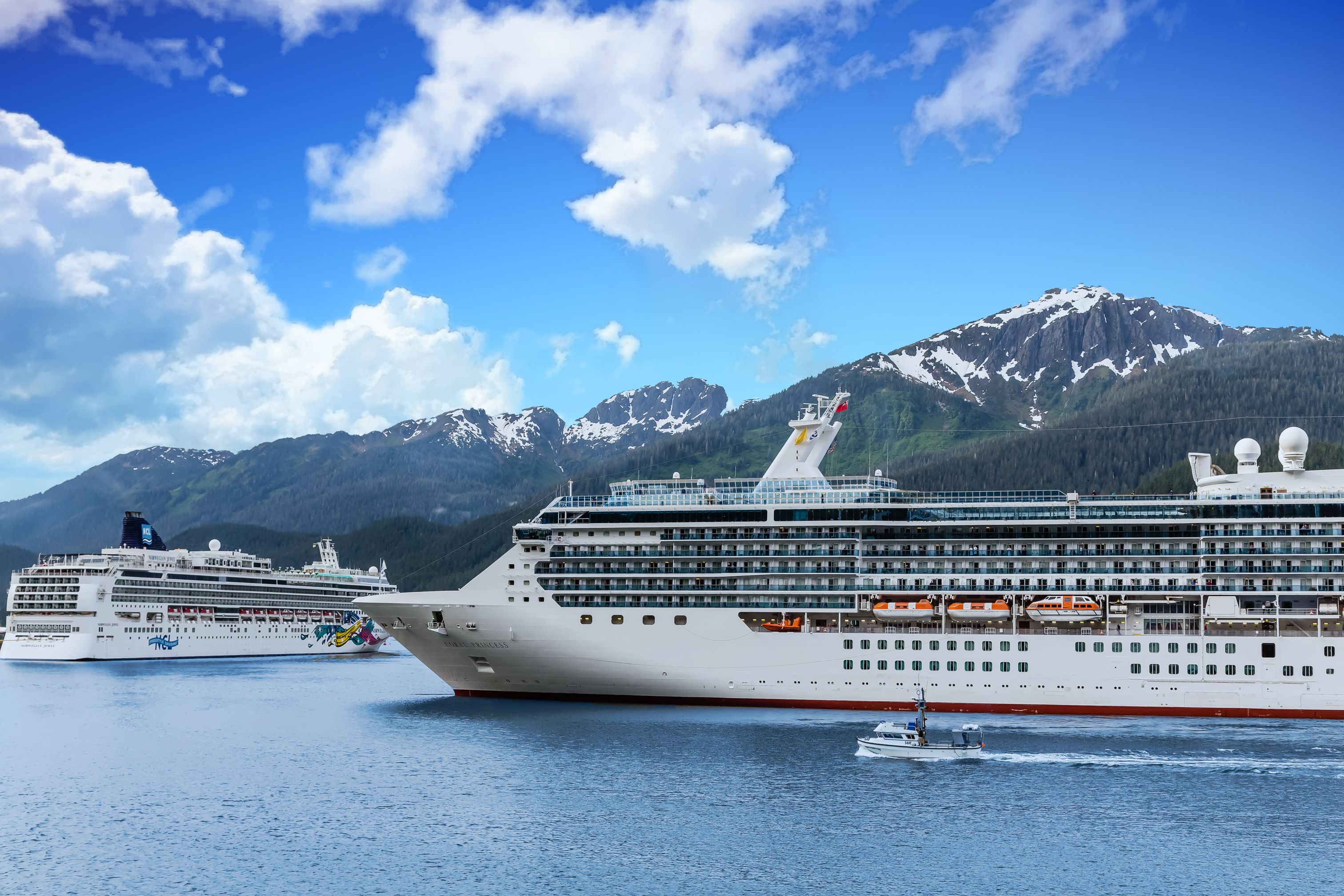 Cruise ships sailing through Alaska’s Inside Passage with snow-capped mountains and scenic coastal views near Juneau port.