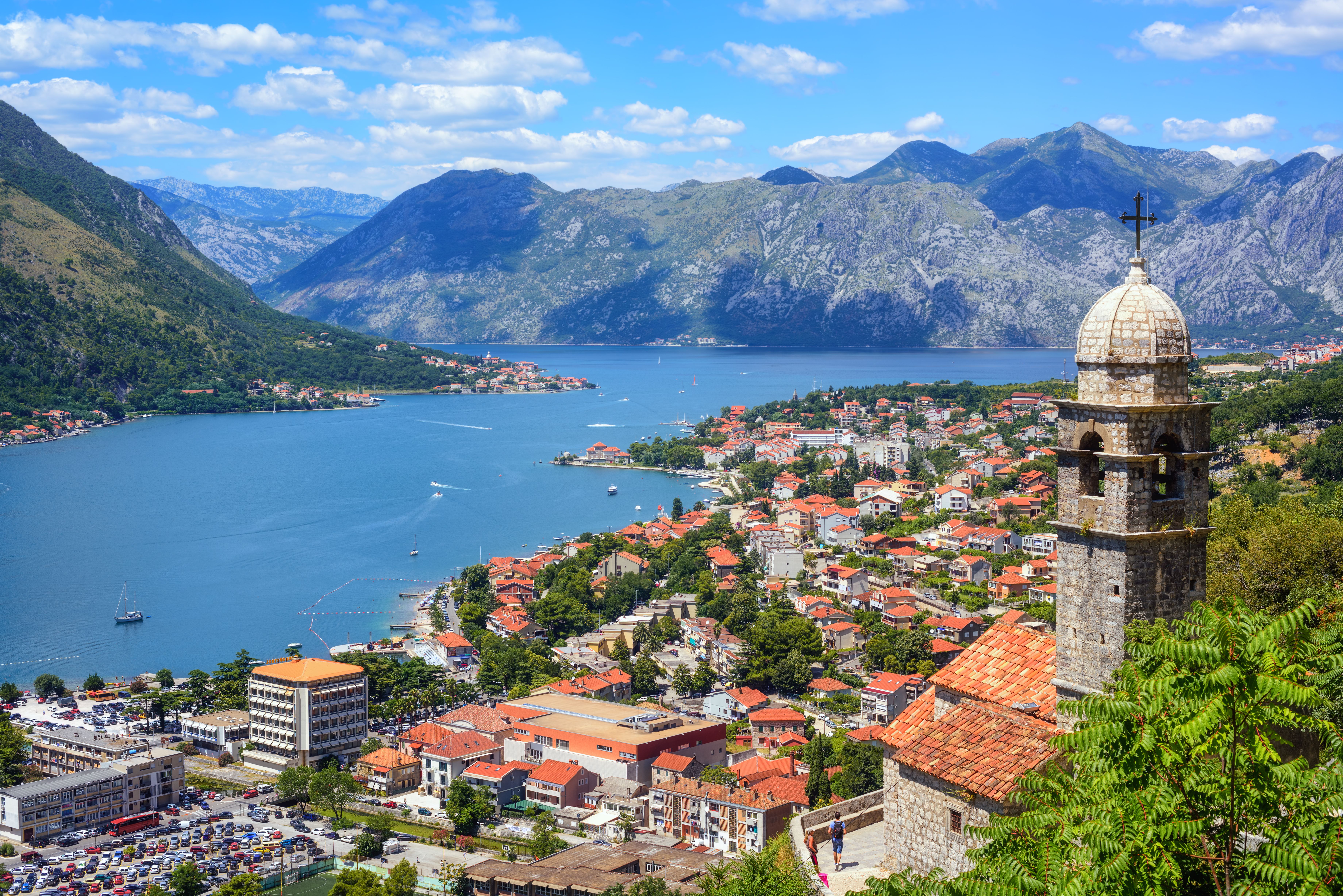 anoramic view of Kotor Bay, Montenegro with historic church tower, red-roofed villages and dramatic Adriatic mountains on a Montenegro shore excursion.