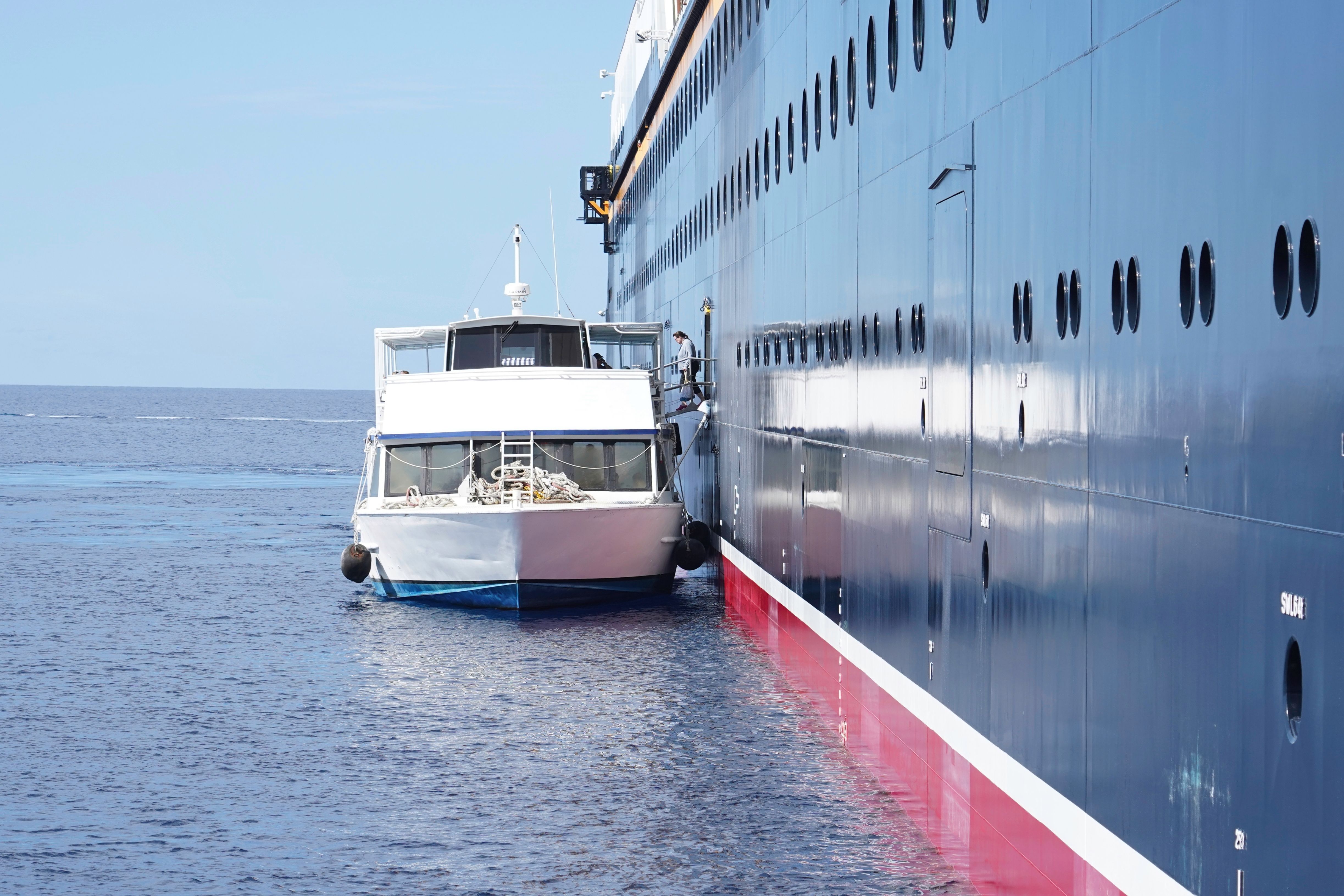 Cruise ship tender boat alongside a cruise vessel at sea, providing passenger transfer for shore excursions and port-of-call access.