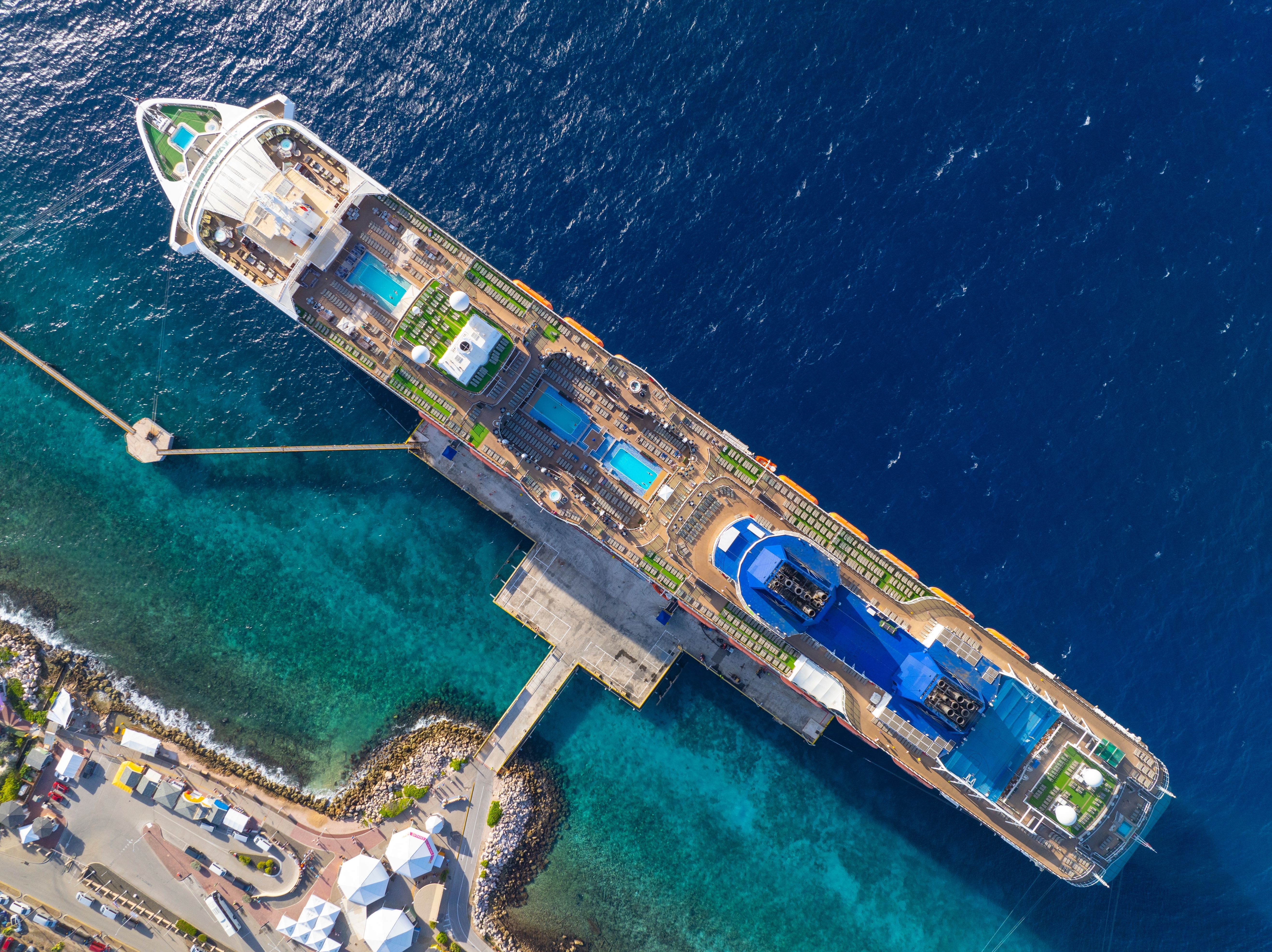 Aerial view of a cruise ship docked at Curaçao cruise port, surrounded by vibrant turquoise Caribbean waters and the island coastline.