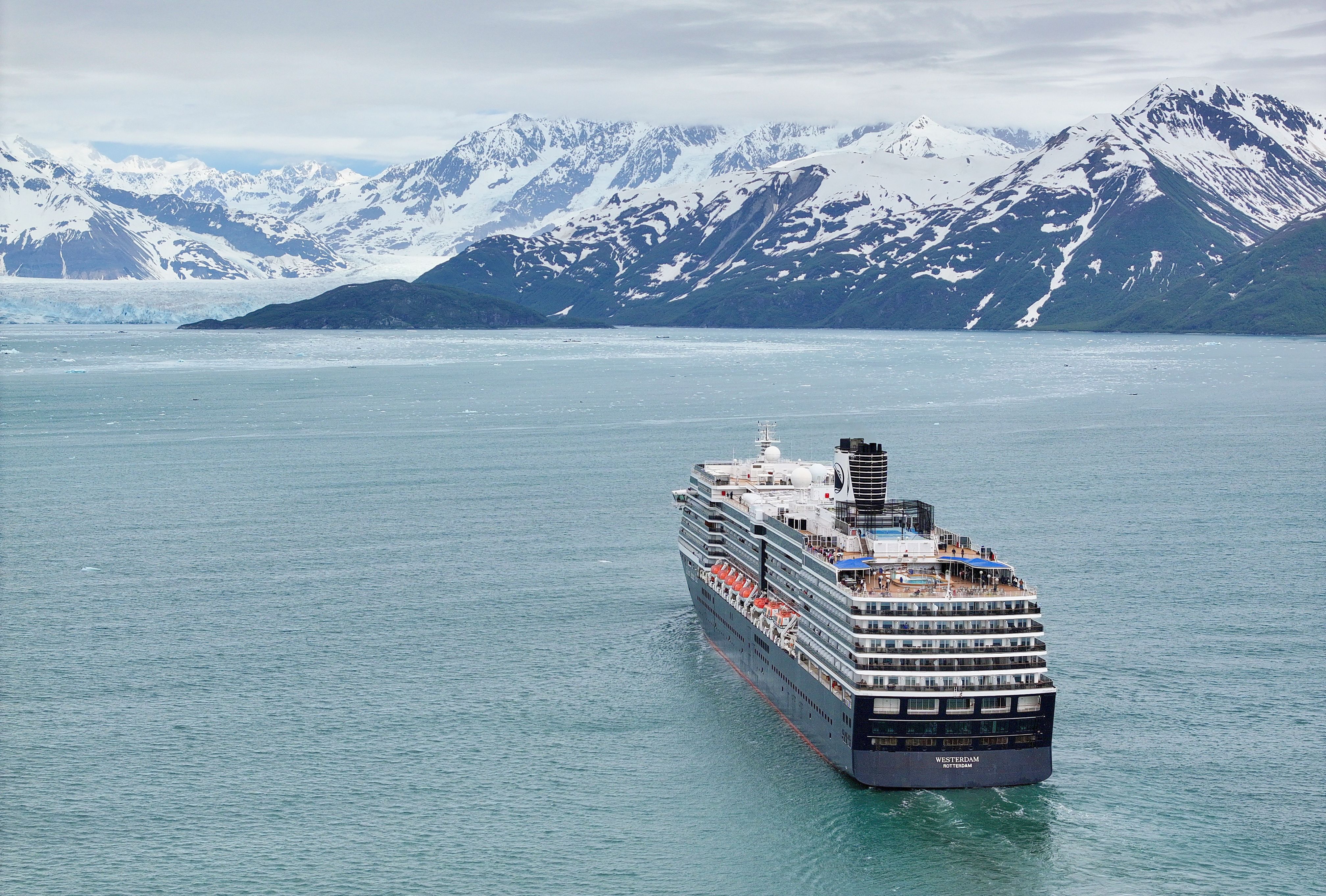 Holland America Line Westerdam cruising through Alaska’s icy waters, surrounded by glaciers and dramatic snow-covered mountains.