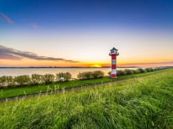 Rot-wei&szlig;er Leuchtturm am Wasser bei Sonnenuntergang an der Elbe