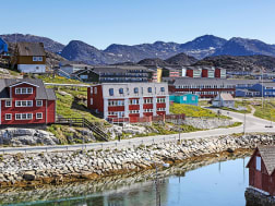 Paamiut / Frederiksh&aring;b, Gr&ouml;nland - K&uuml;stenstra&szlig;e mit roten H&auml;usern und klarem Wasser im Fjord
