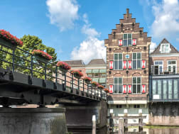 Gorinchem, Niederlande - Historisches Giebelhaus an Kanal neben Br&uuml;cke mit Blumen