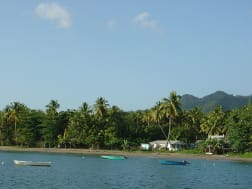 Portsmouth, Dominica &ndash; Costa tropical con palmeras, barcos y monta&ntilde;as verdes