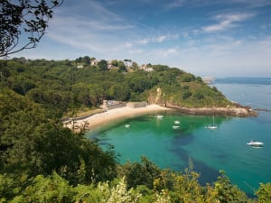 Guernsey, Kanalinseln &ndash; gr&uuml;ne Bucht mit Sandstrand und Booten vor steiler K&uuml;ste