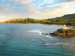 Amber Cove, Dominikanische Republik &ndash; Wei&szlig;er Turm auf felsiger Kapspitze &uuml;ber ruhigem Strand und gr&uuml;nem Hang