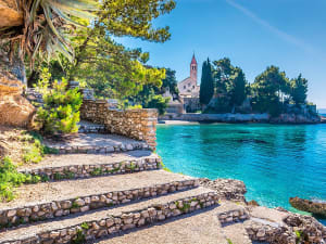 Bol, Kroatien &ndash; Steintreppen f&uuml;hren zur Kirche am klaren K&uuml;stenwasser