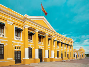 Barranquilla, Kolumbien - Gelbes Zollgeb&auml;ude mit wei&szlig;en S&auml;ulen und Flagge