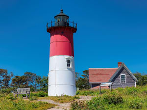 Falmouth, England &ndash; Rot-wei&szlig;er Leuchtturm vor klarem blauen Himmel neben einem kleinen H&auml;uschen