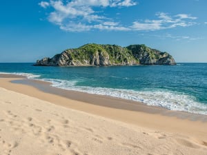 Huatulco, Mexiko &ndash; einsame Felsinsel liegt vor leerem Sandstrand im Sonnenlicht