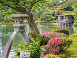 Kanazawa, Japan &ndash; Steinlaterne am Wasser im Kenroku-en mit Blick auf Teepavillon