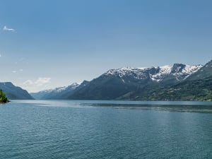Hardangerfjord, Norwegen &ndash; Gr&uuml;nes Ufer trifft auf tiefblauen Fjord und wei&szlig;e Gipfel