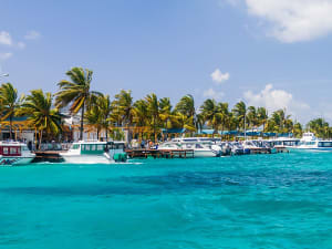 Mal&eacute;, Malediven &ndash; lebhafte Promenade mit Palmen und Booten am klaren Hafenwasser