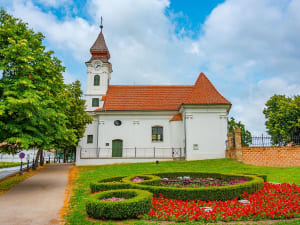 Vukovar, Kroatien &ndash; barocke Kirche mit rotem Ziegeldach und bunter Blumenuhr im Park